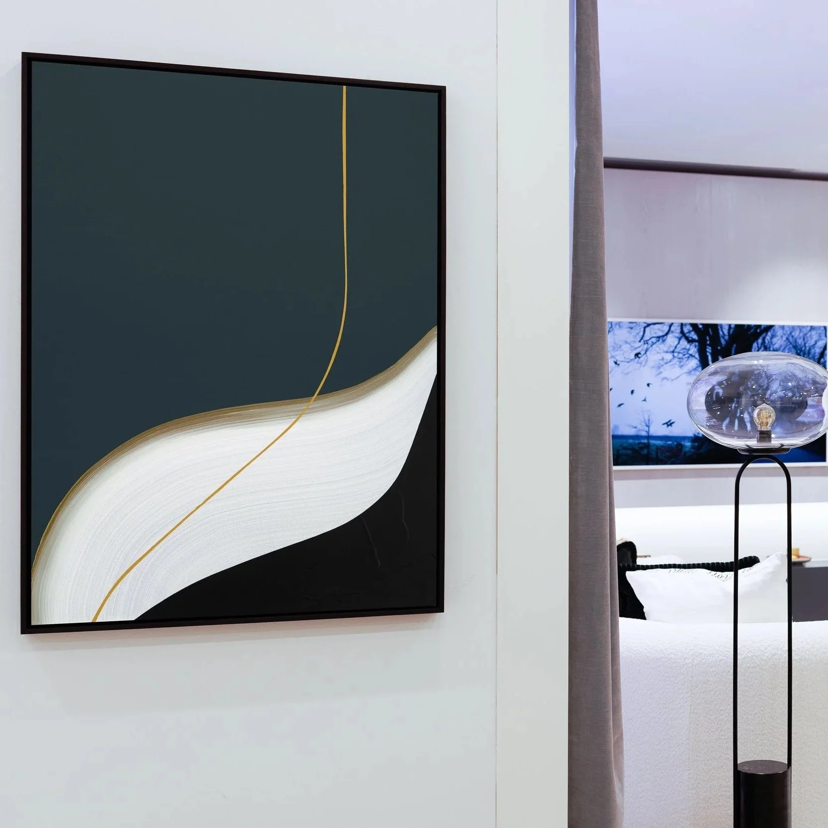 Amy Stewart abstract abstract wall art with curved lines in black, white, and gold, a tall lamp with a transparent glass shade, and a bedroom visible through a curtain with a landscape TV screen showing trees and birds in a modern setting.