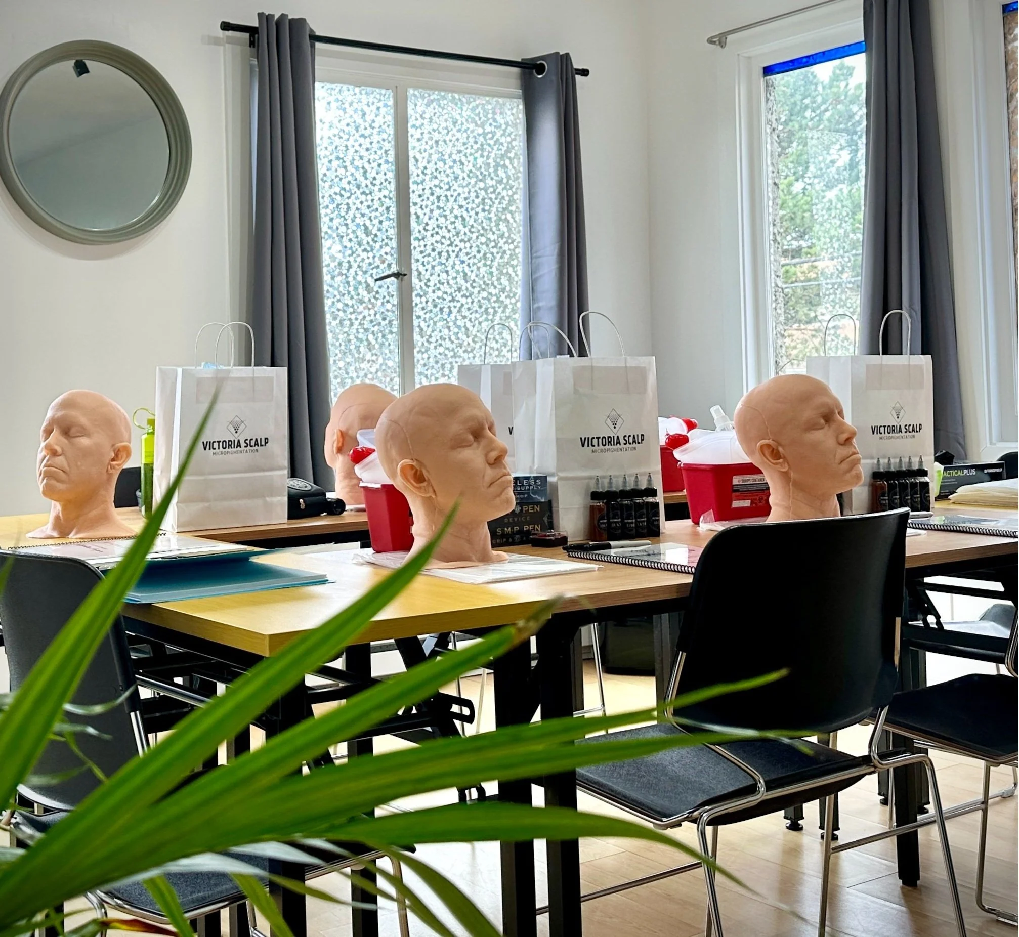 Victoria Scalp training studio in Victoria B.C. The bright and welcoming room shows the materials offered in training, including the use of practice heads for the day, as well as gift bags with take home inks, supplies and machine.