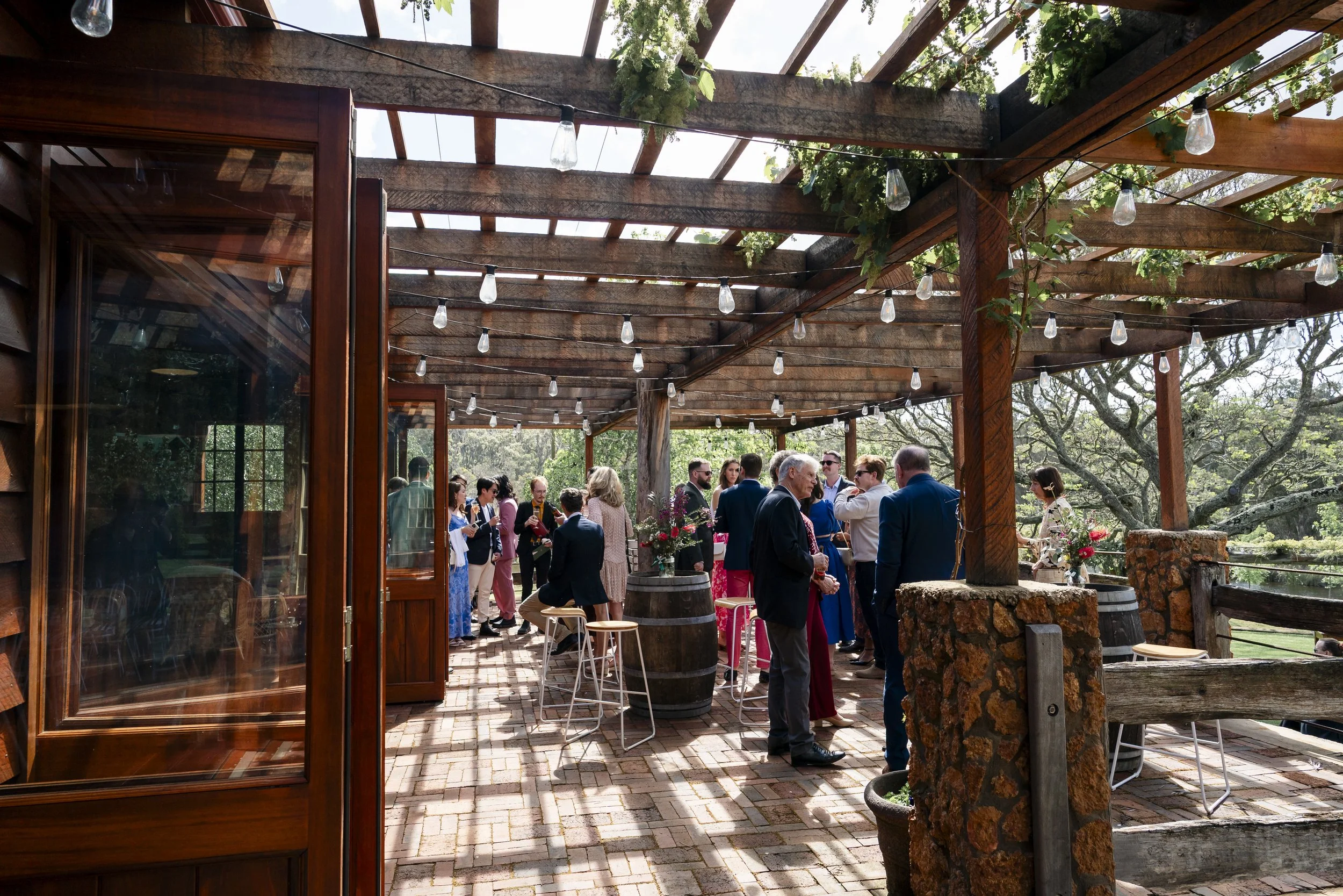 Stone and Wooden Terrace setting with bi folding jarrah doors opening up from a country style barn.  Stools and wine barrels ready for guests to sit and enjoy  wedding drinks
