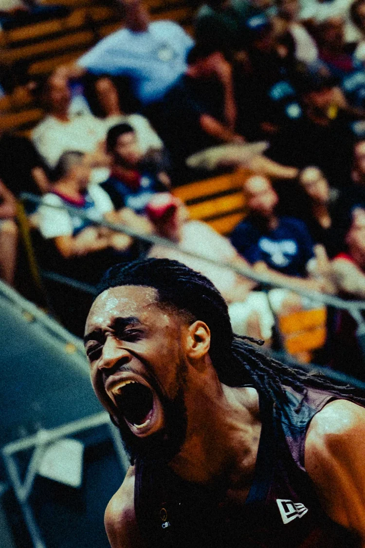 Photographe sportif Montréal - anais fabra.
Un homme avec des dreadlocks en train de crier, dans un environnement intérieur avec des spectateurs en arrière-plan