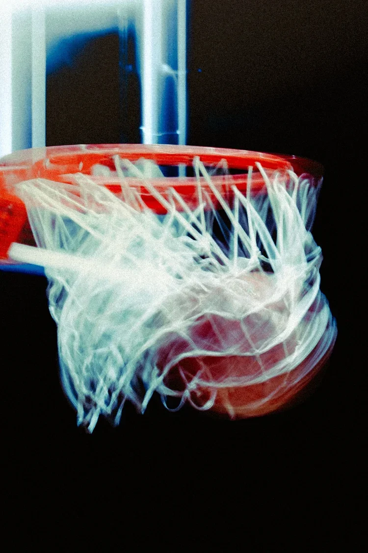 Table de basket-ball avec un panier orange et un filet, vu de près dans une salle de sport.
Photographe sportif Montréal - anais fabra