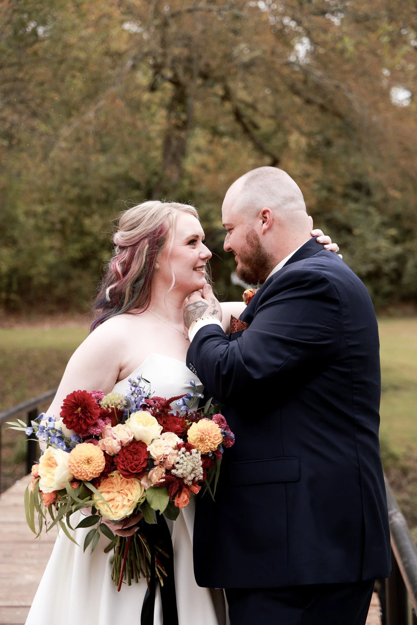 Groom holding brides face and smilling at each other 