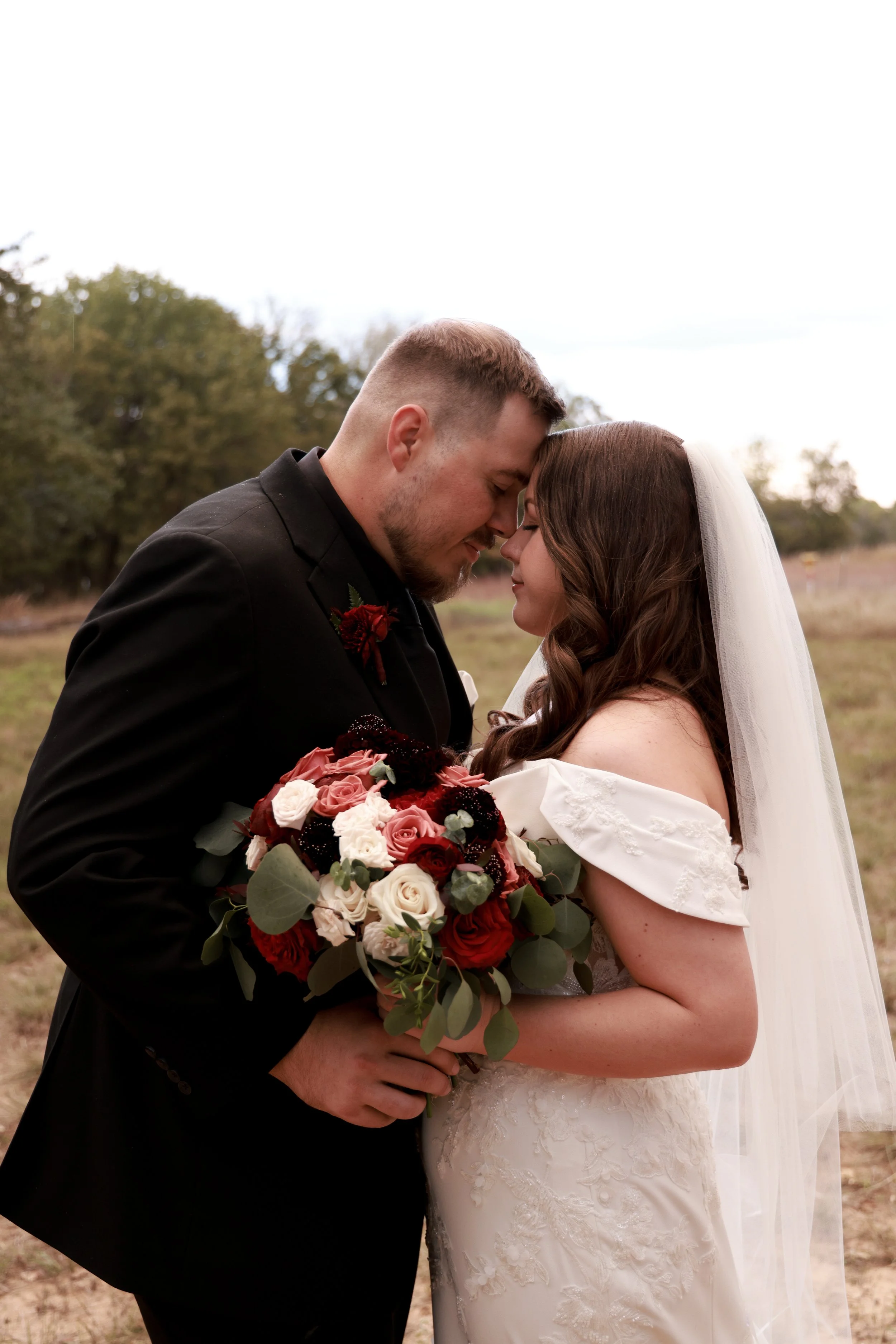 GROOM AND BRIDE MAKING NOSES AND HOLDING BOUQUET