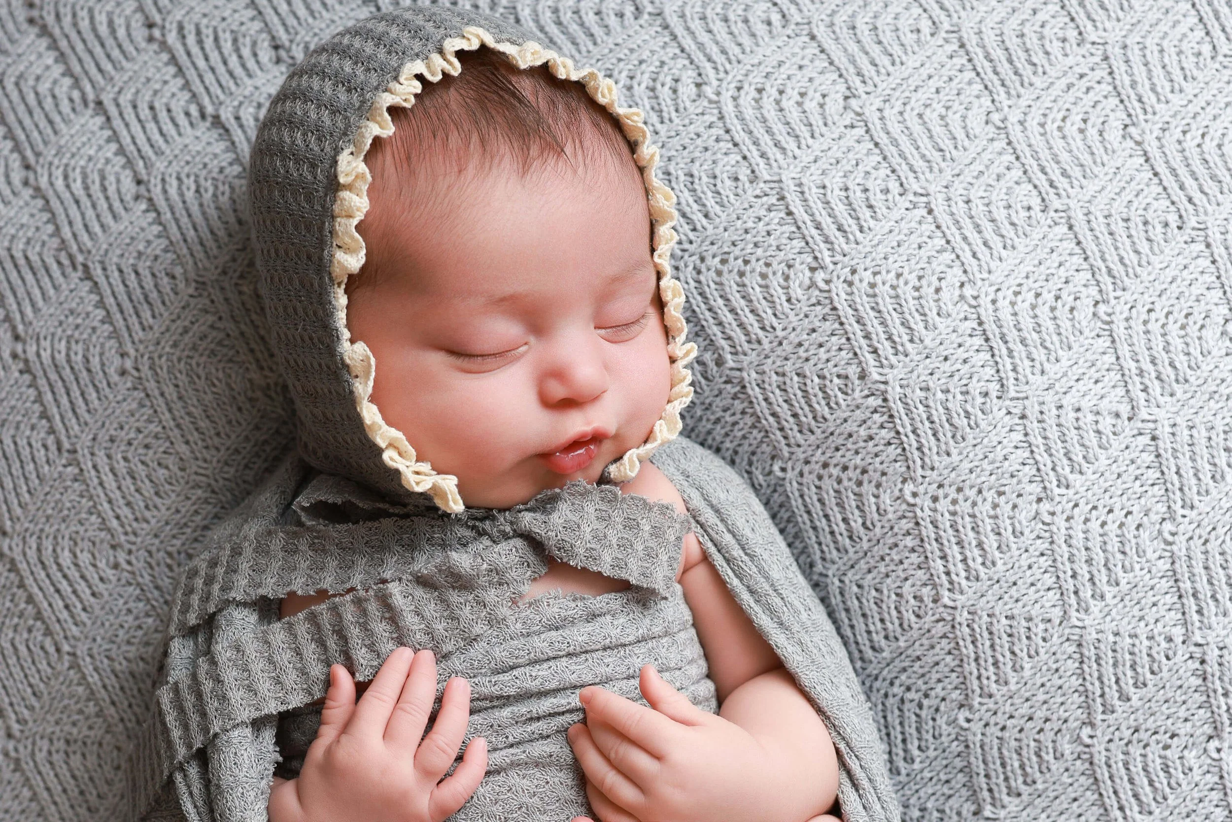 Newborn baby girl wearing gray bonnet in Fort Worth