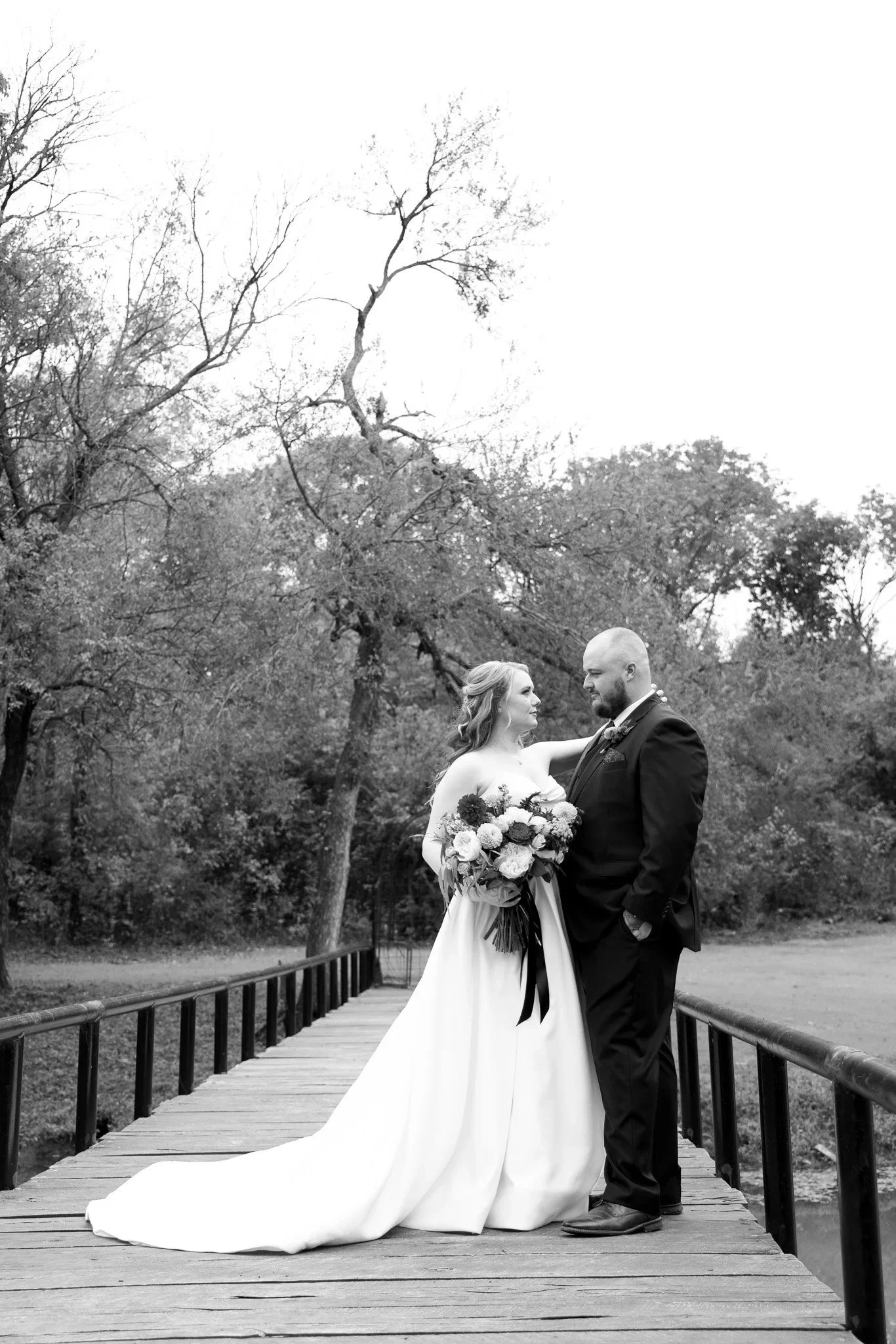 Bride and groom on a bridge holding bouquet by Fort Worth wedding photographer