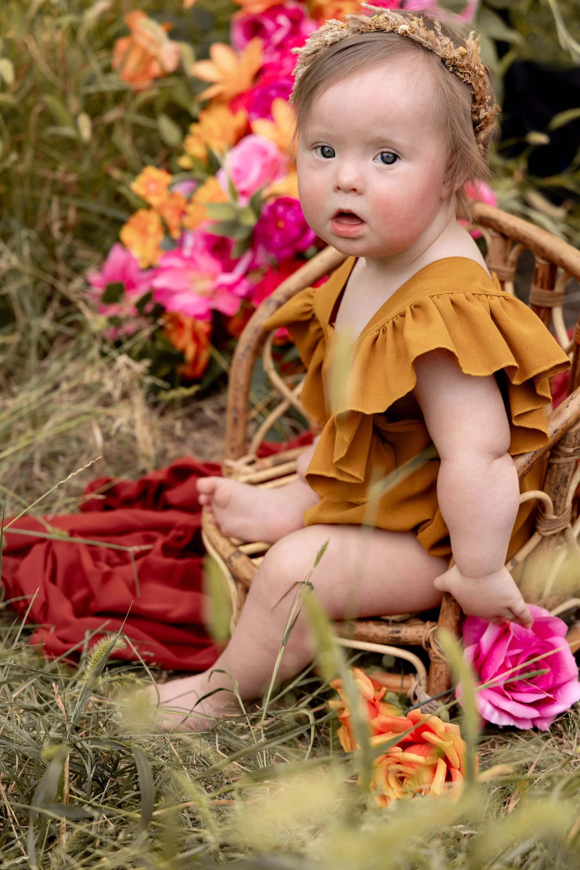 toddler girl sitting on tiny chair on the grass looking at the camera in Grapevine Texas
