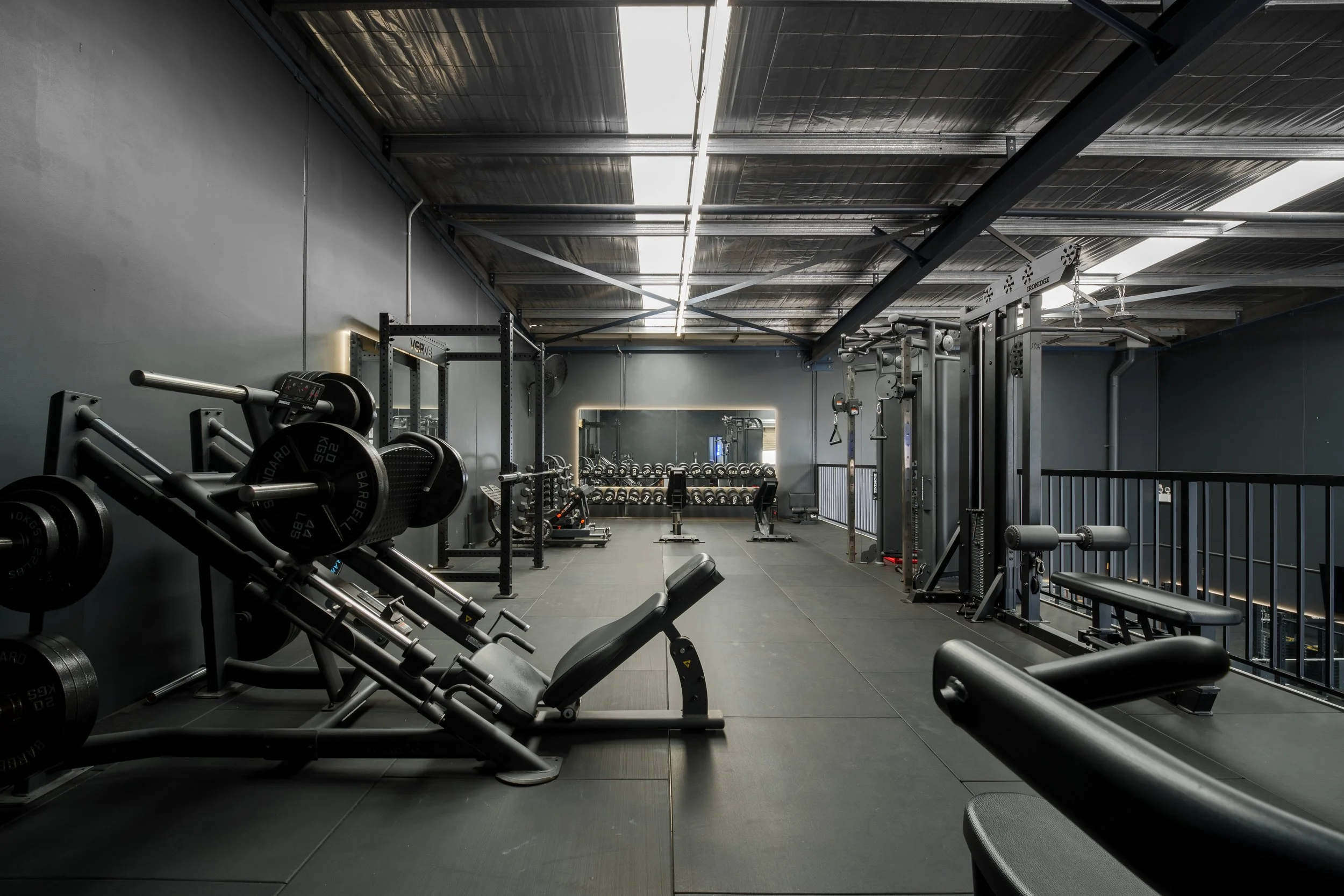 Empty gym with black workout equipment, benches, dumbbells, and weight machines in a modern fitness center.