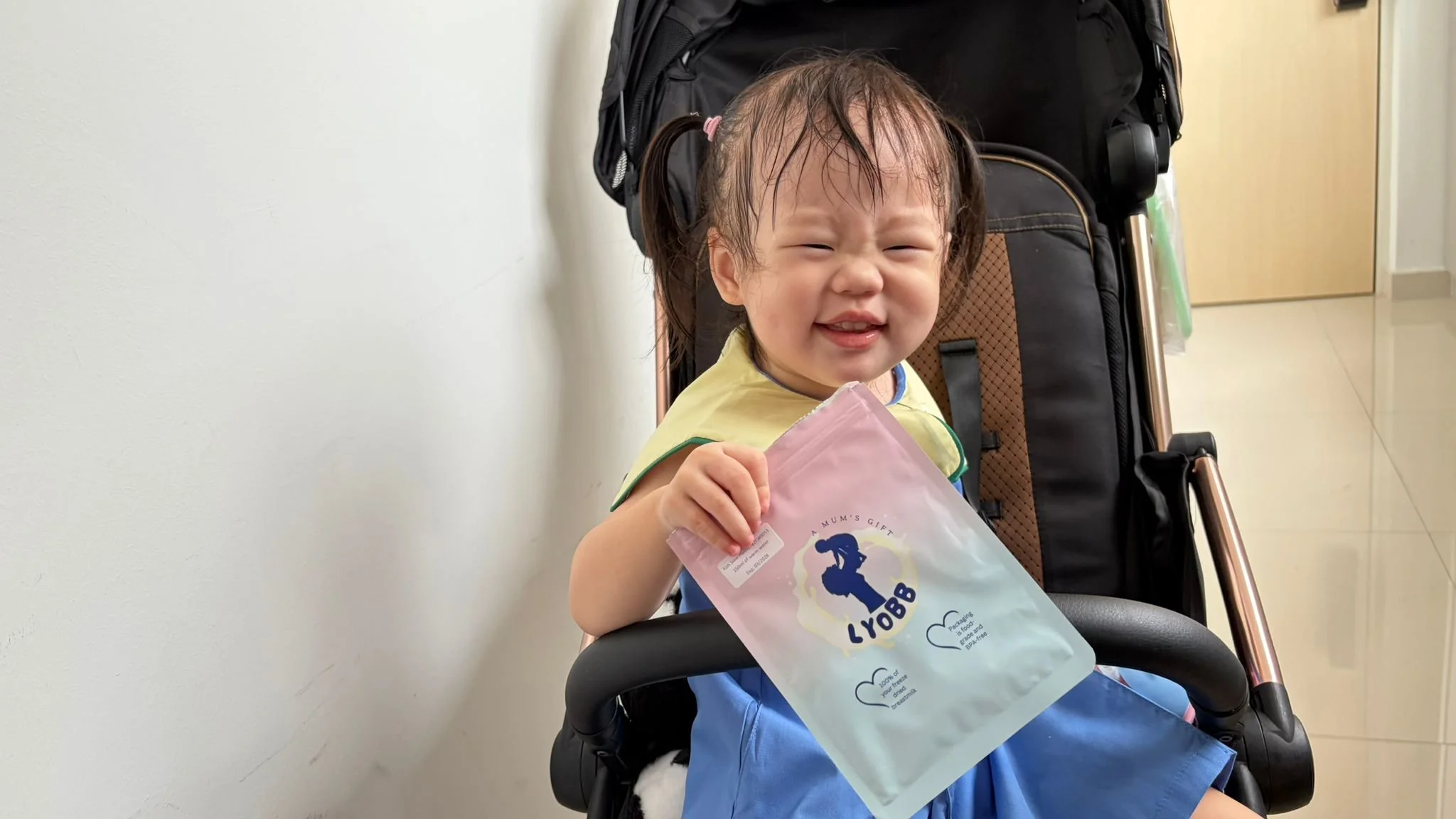 Baby holding travel-friendly LyoBB breastmilk powder packaging