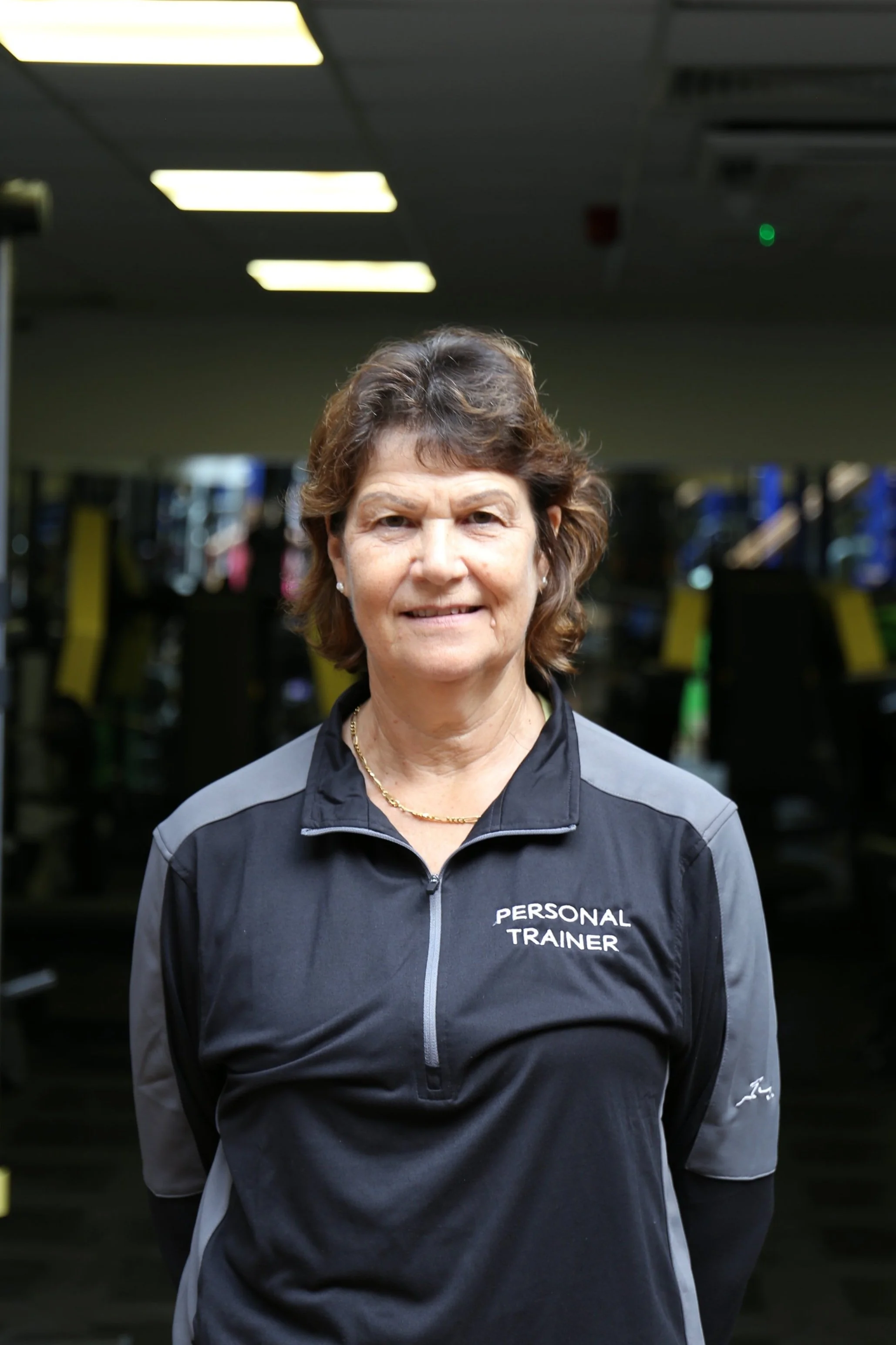 Woman wearing a 'Personal Trainer' shirt in a gym
