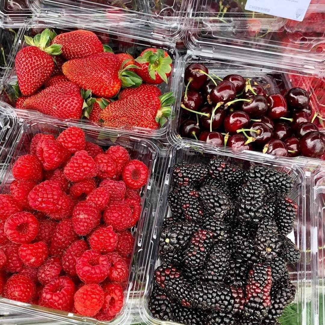 Assorted fresh berries including strawberries, cherries, raspberries, and blackberries in plastic containers.