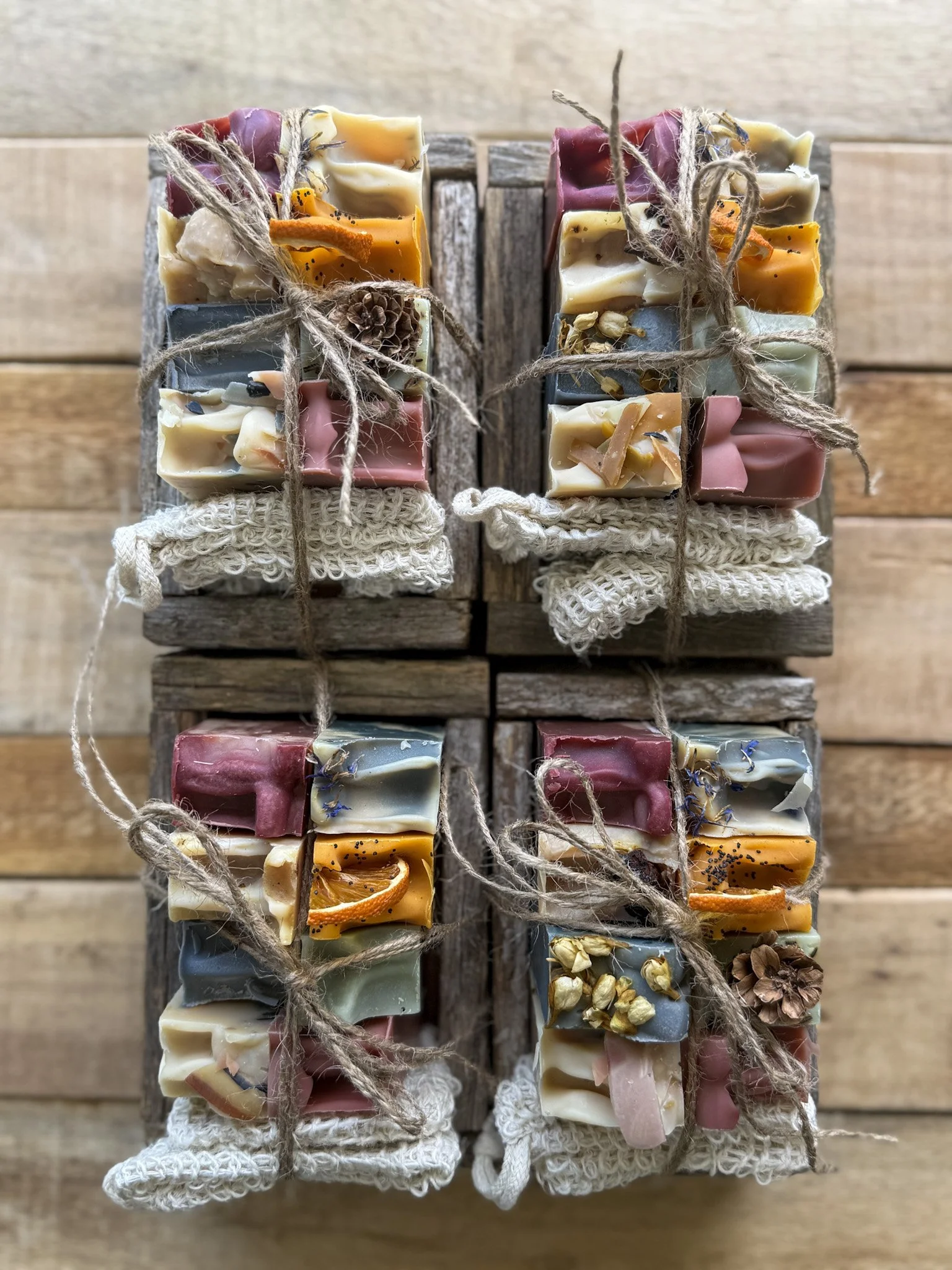 Three bundles of artisanal soap bars tied with twine on a wooden surface.