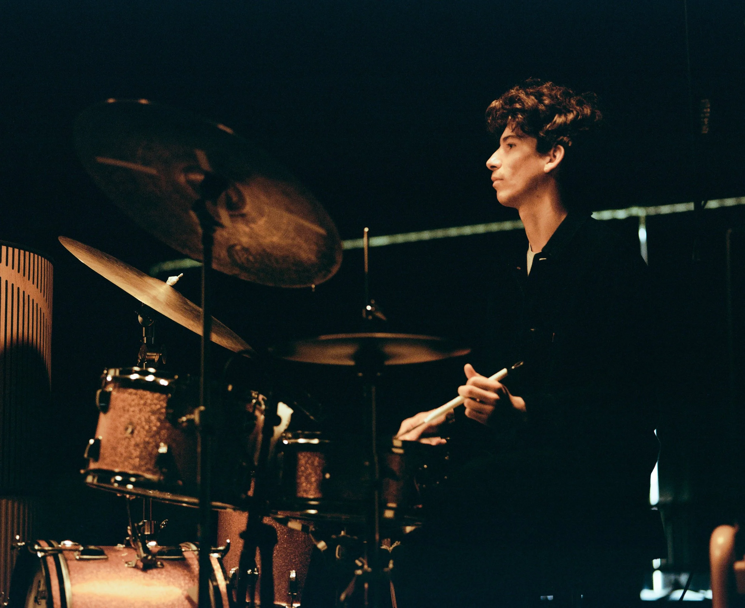 Ein junger Mann spielt auf einem Schlagzeug in einem dunklen Raum.