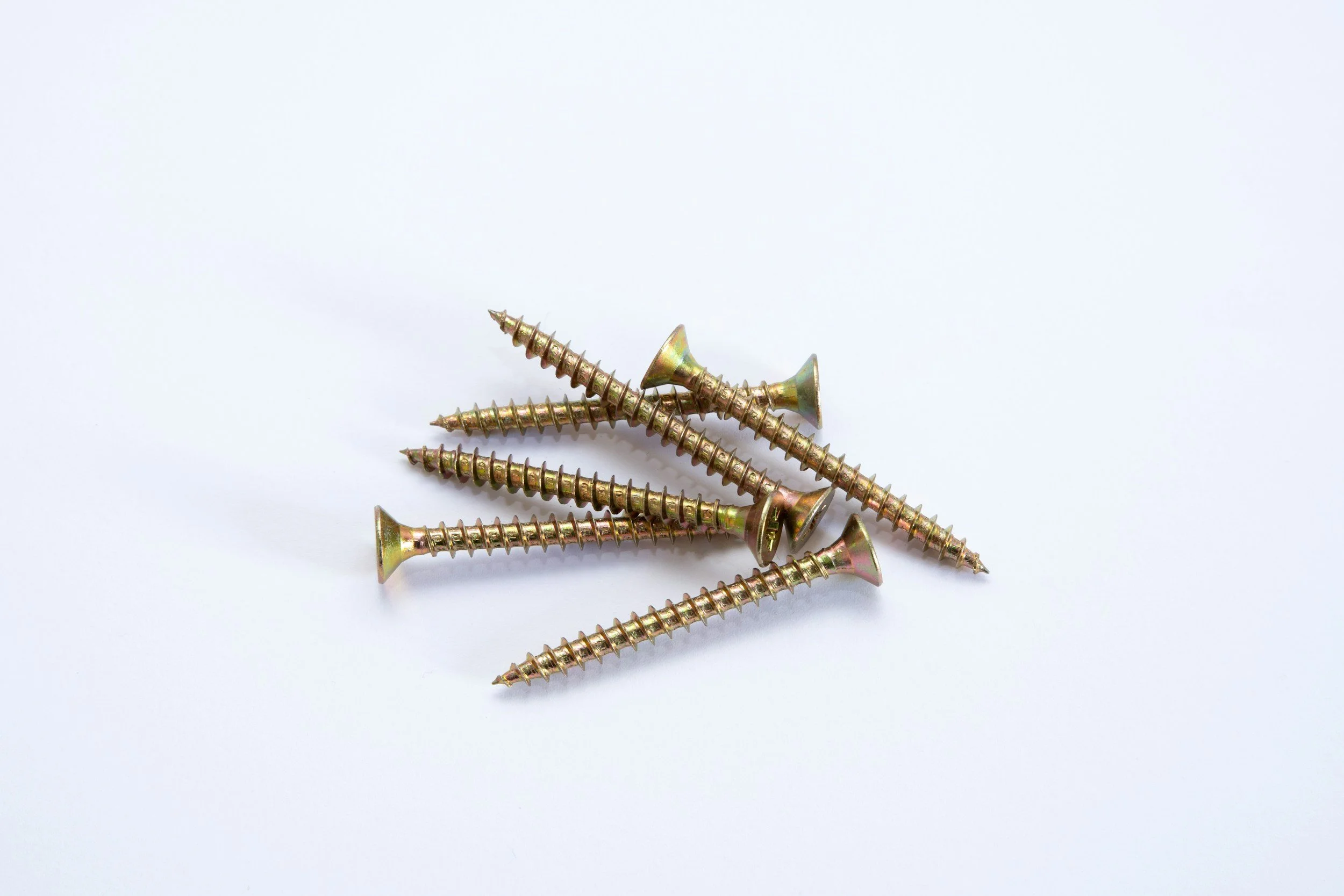 Seven gold-colored wood screws arranged on a white background.