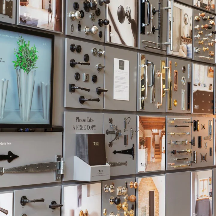 Display of various door hardware and handles on a wall of sample boards in a showroom.