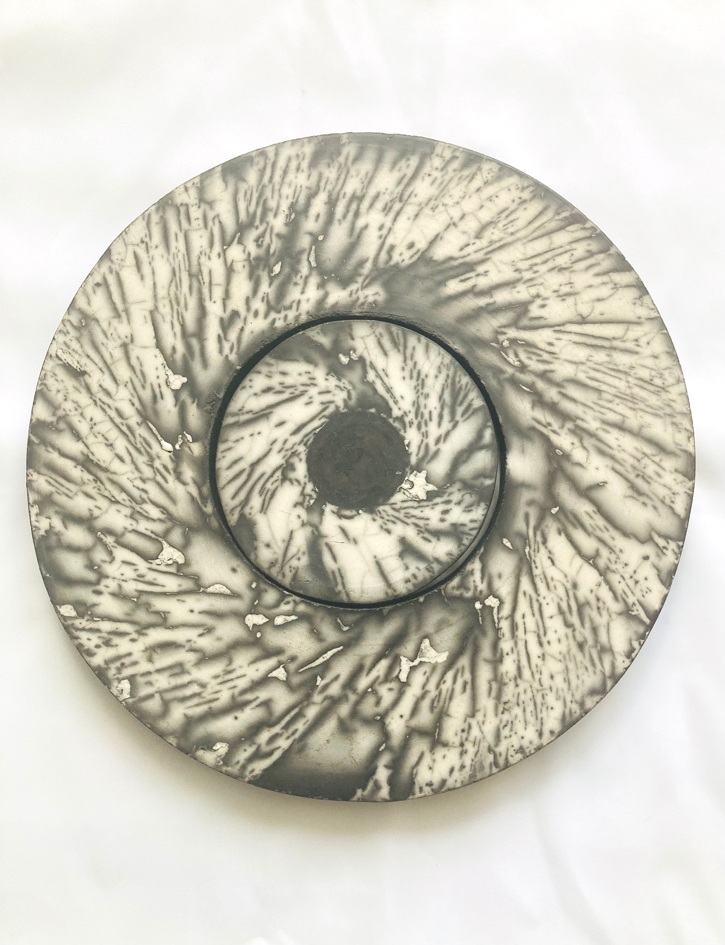 Disc shaped wall piece made of concentric circles in naked raku technique with spiralling black and white markings