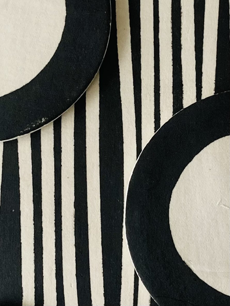 A section of a porcelain wall panel showing a black and white striped ground with black and white semi circles mounted on top