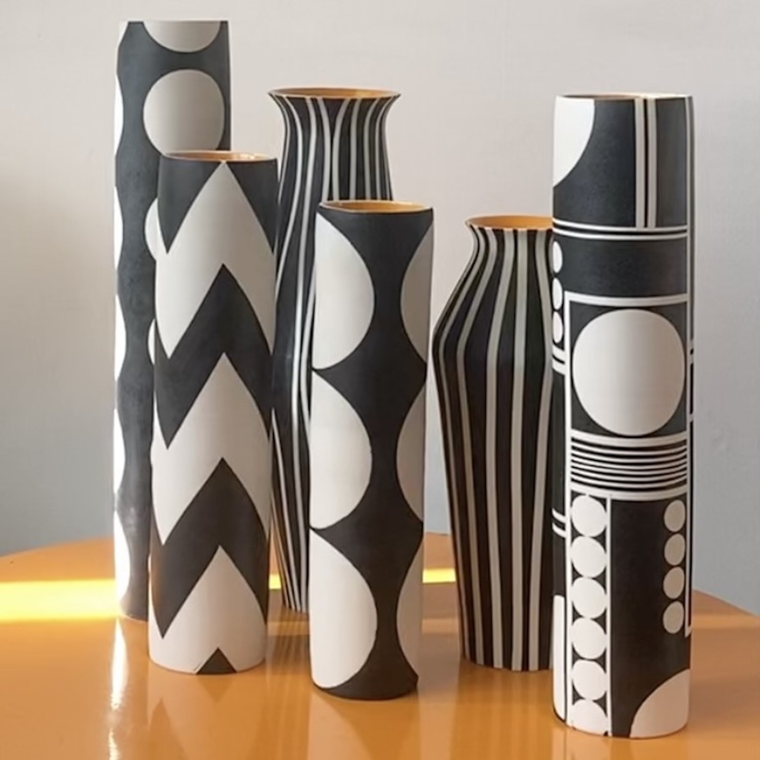 6 tall porcelain vases with bold geometric patterns in black and white with glazed orange interior. Mid century inspired