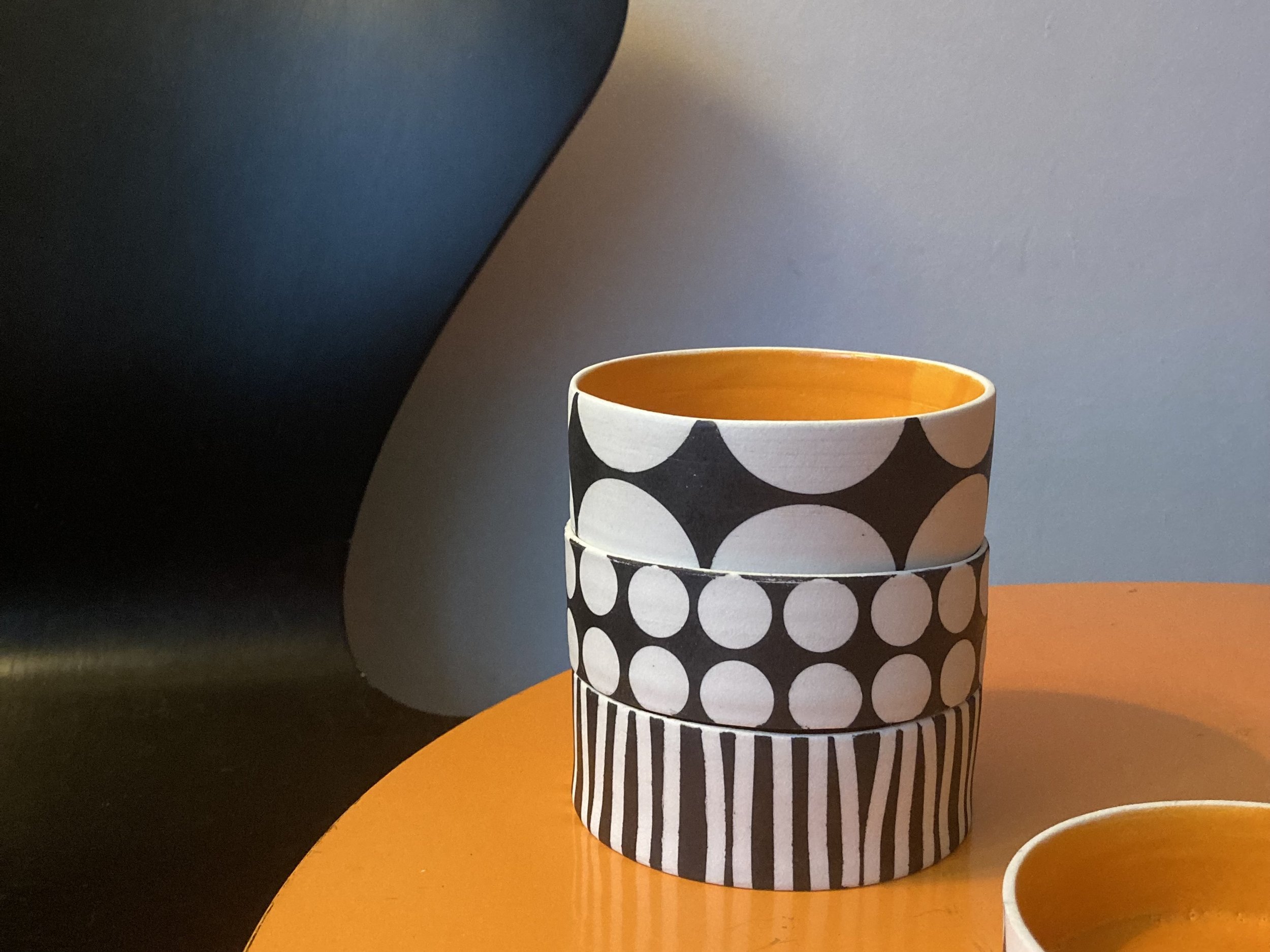 3 small dishes with spot and stripe black and white bold geometric patterns and orange glazed interior