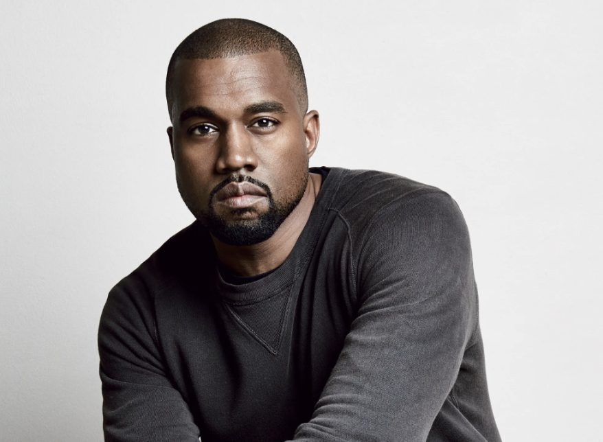 Portrait of a man with short hair and a beard, wearing a black long-sleeve shirt, sitting against a plain light-colored background.