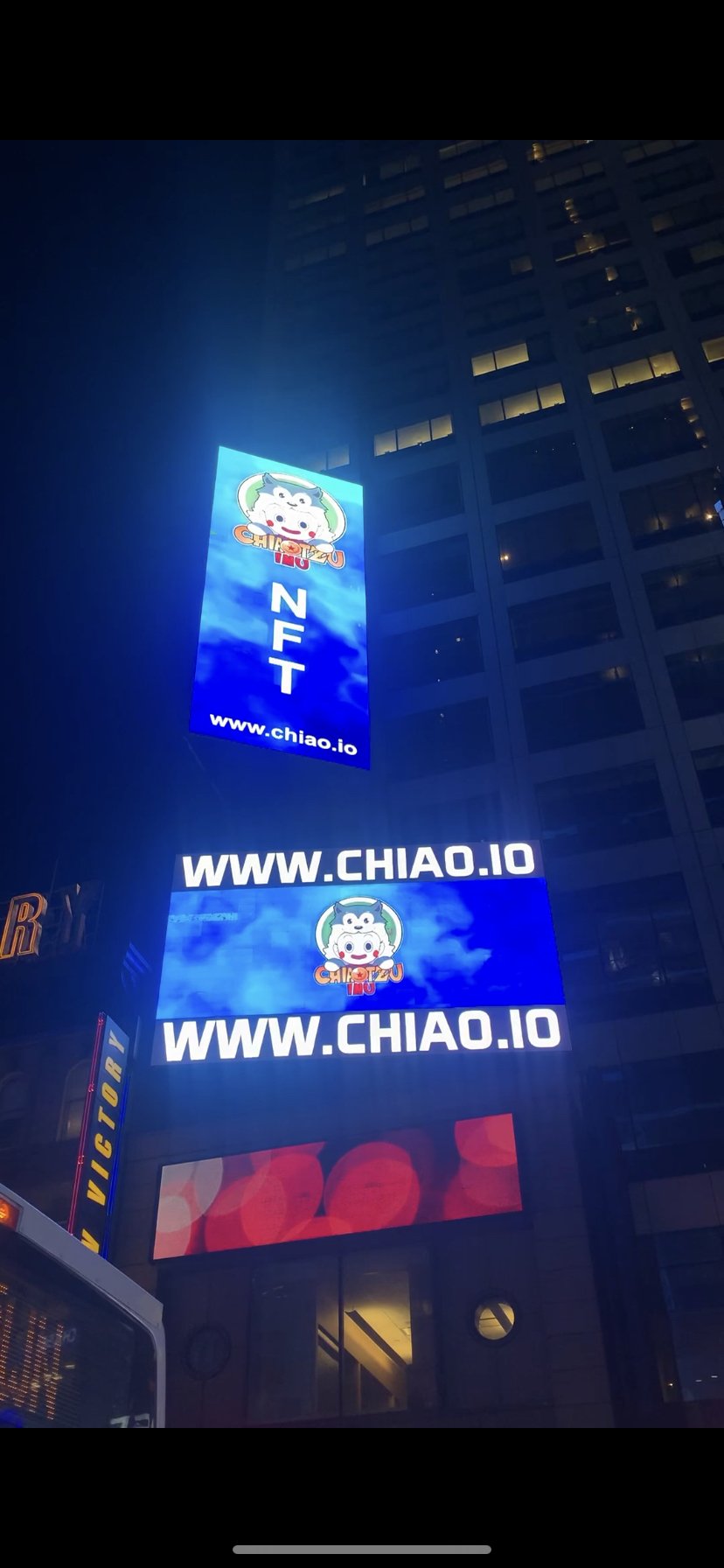Nighttime city scene with illuminated digital billboards displaying a logo of a cartoon cow's face with the text 'Chiato' and website www.chiao.io.
