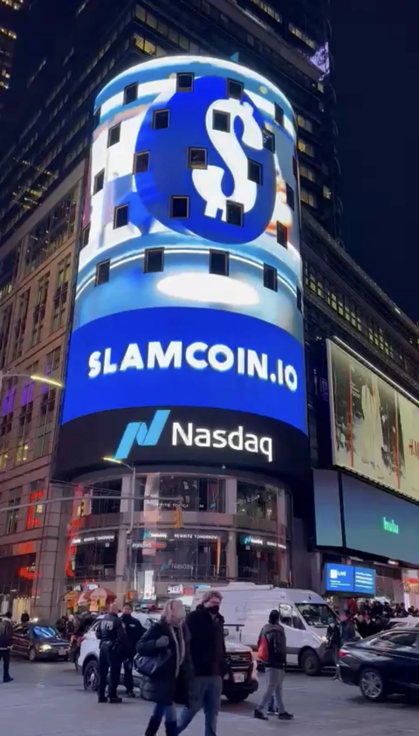 Digital billboard advertising SlamCoin.io and Nasdaq in Times Square, New York City, at night, with pedestrians and cars on the street.