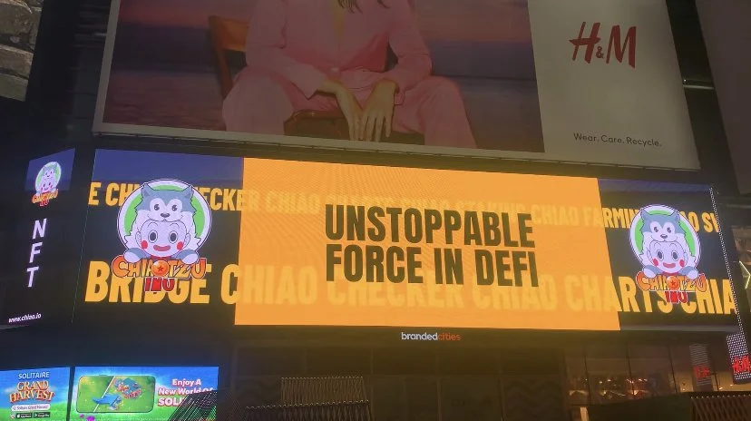 Digital billboard displaying bright yellow background with black text reading 'Unstoppable Force in DeFi', and cartoon pig characters on the sides.
