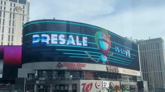 Digital billboard on a city building displaying the word 'DRESALE' and a cartoon character with open arms.