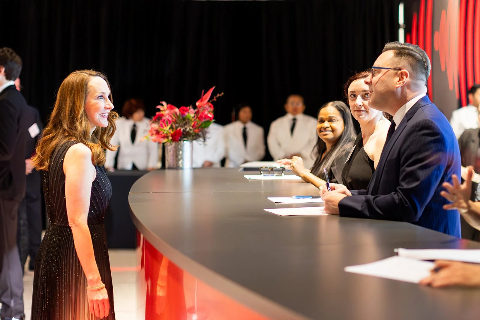 A woman interacts with staff at the event guest check-in counter.