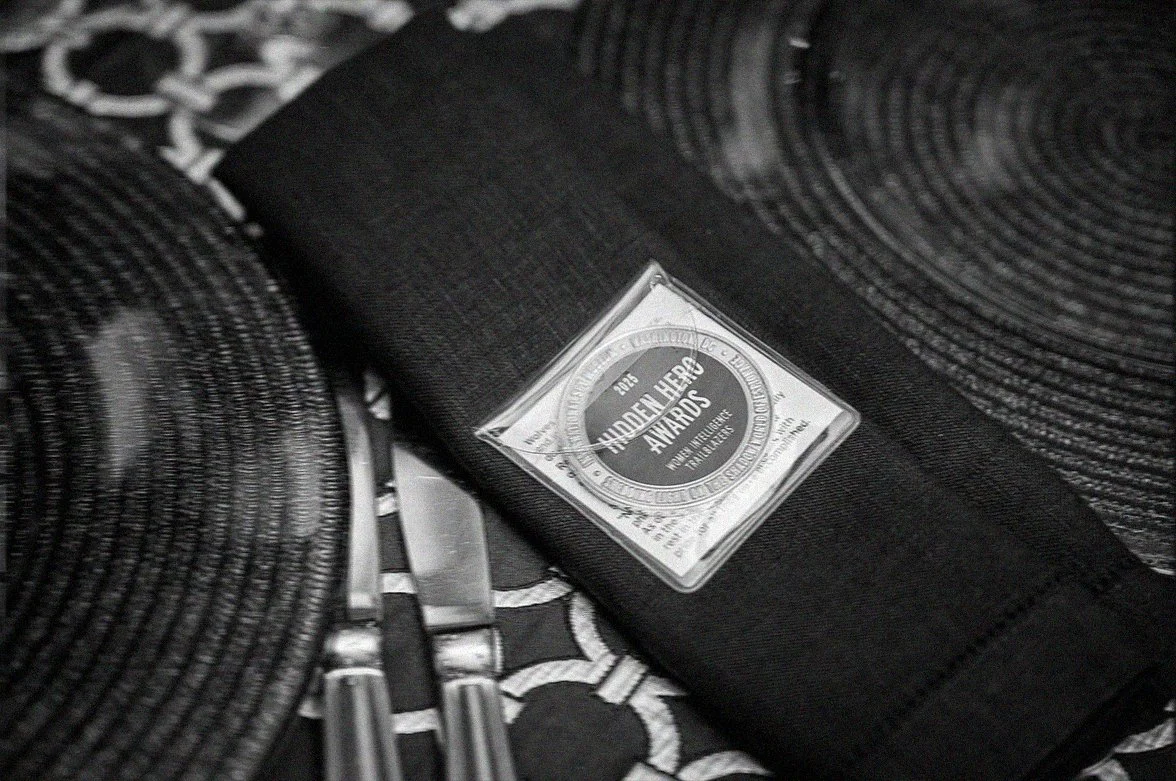 An image of a silver challenge coin sitting on a napkin at a dinner table setting.