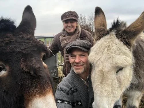 Wim en Sandra, de uitbaters van de Romeinse Katzei, poseren met hun twee ezels in een weiland.