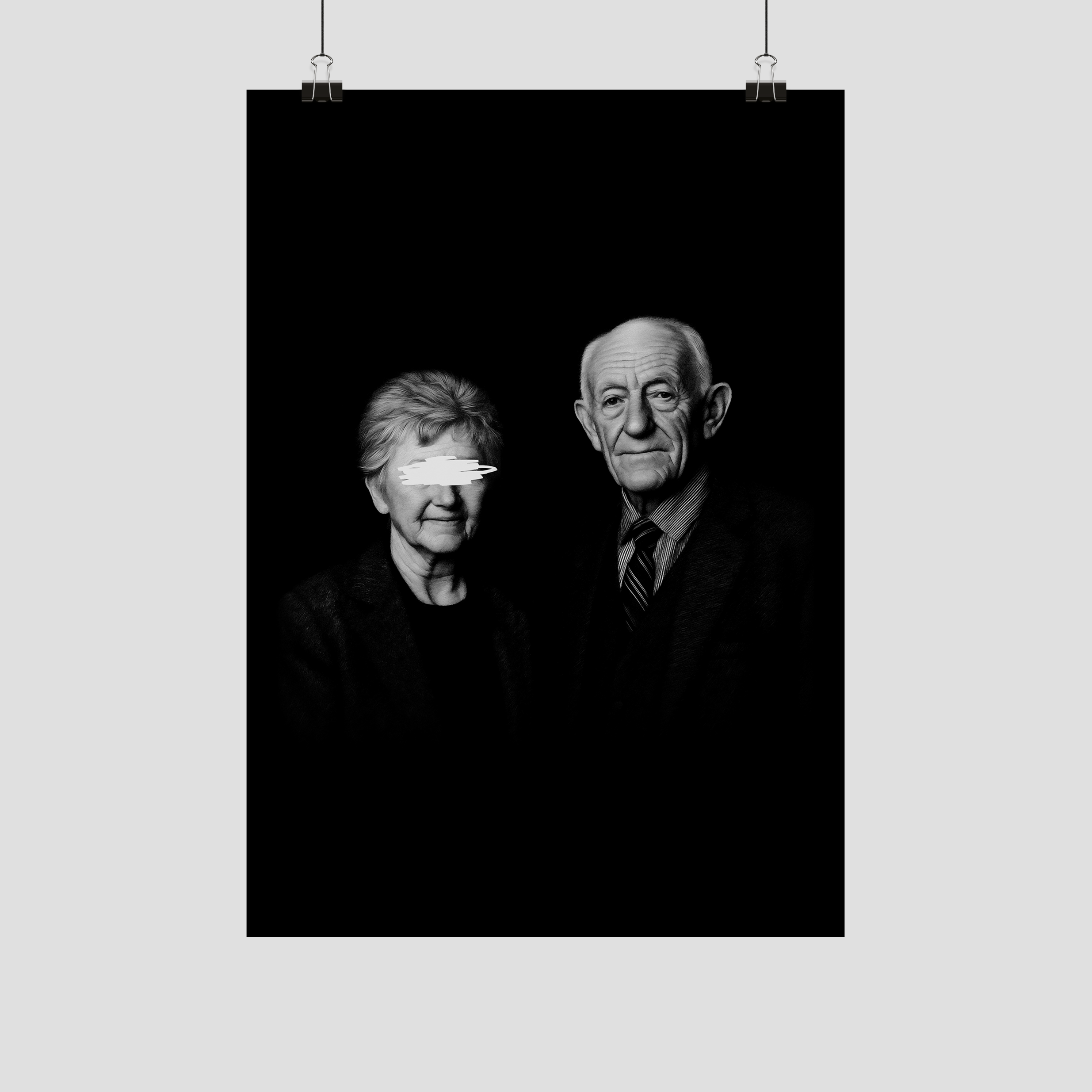 Black and white portrait of an elderly woman and man against a black background, hanging from silver clips.