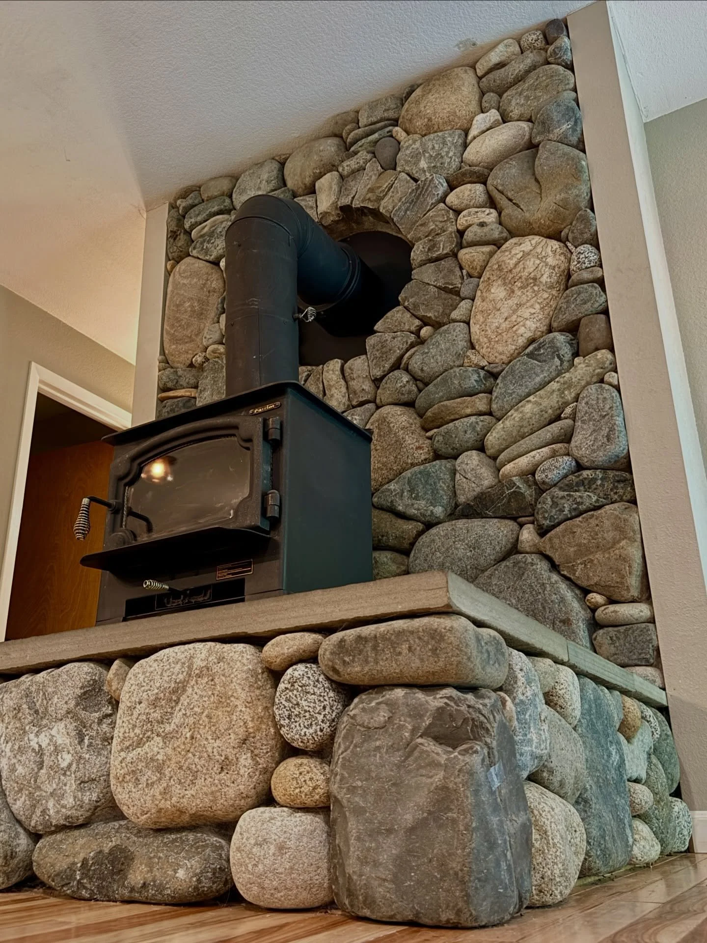 River rock wood stove surround #millerstoneworks #woodstove #riverrock #stonemasonry #interiordesign