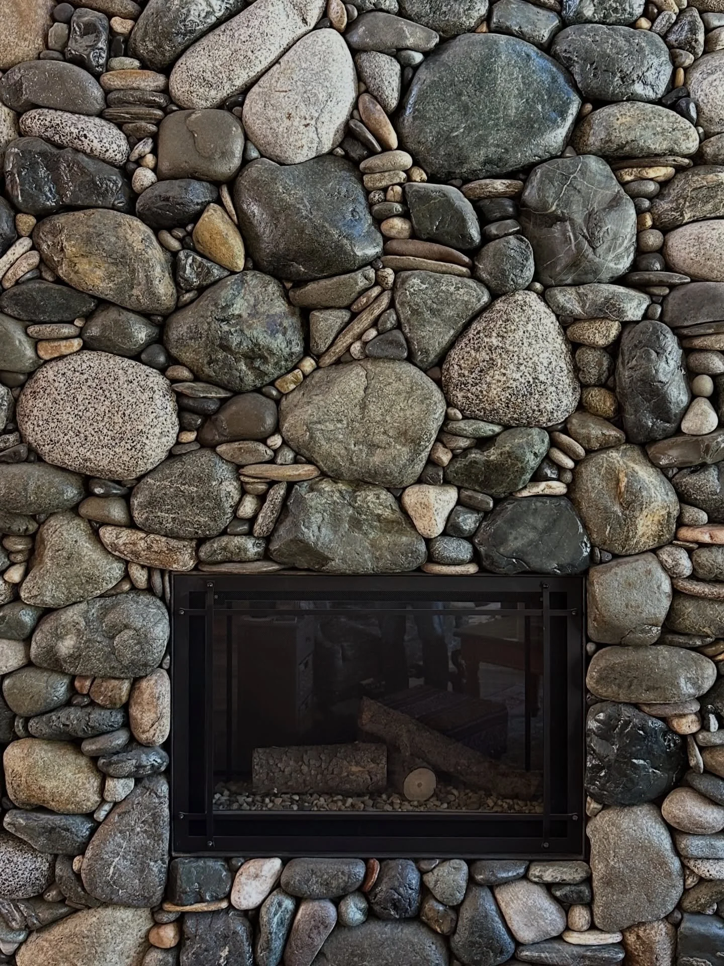 River rock fireplace with a diamond-clear sealer. While most of the stone I lay up stays natural, the option is always available for my clients to use a sealer to achieve this wet look #millerstoneworks #riverrock #fireplace #sealer #stonemasonry