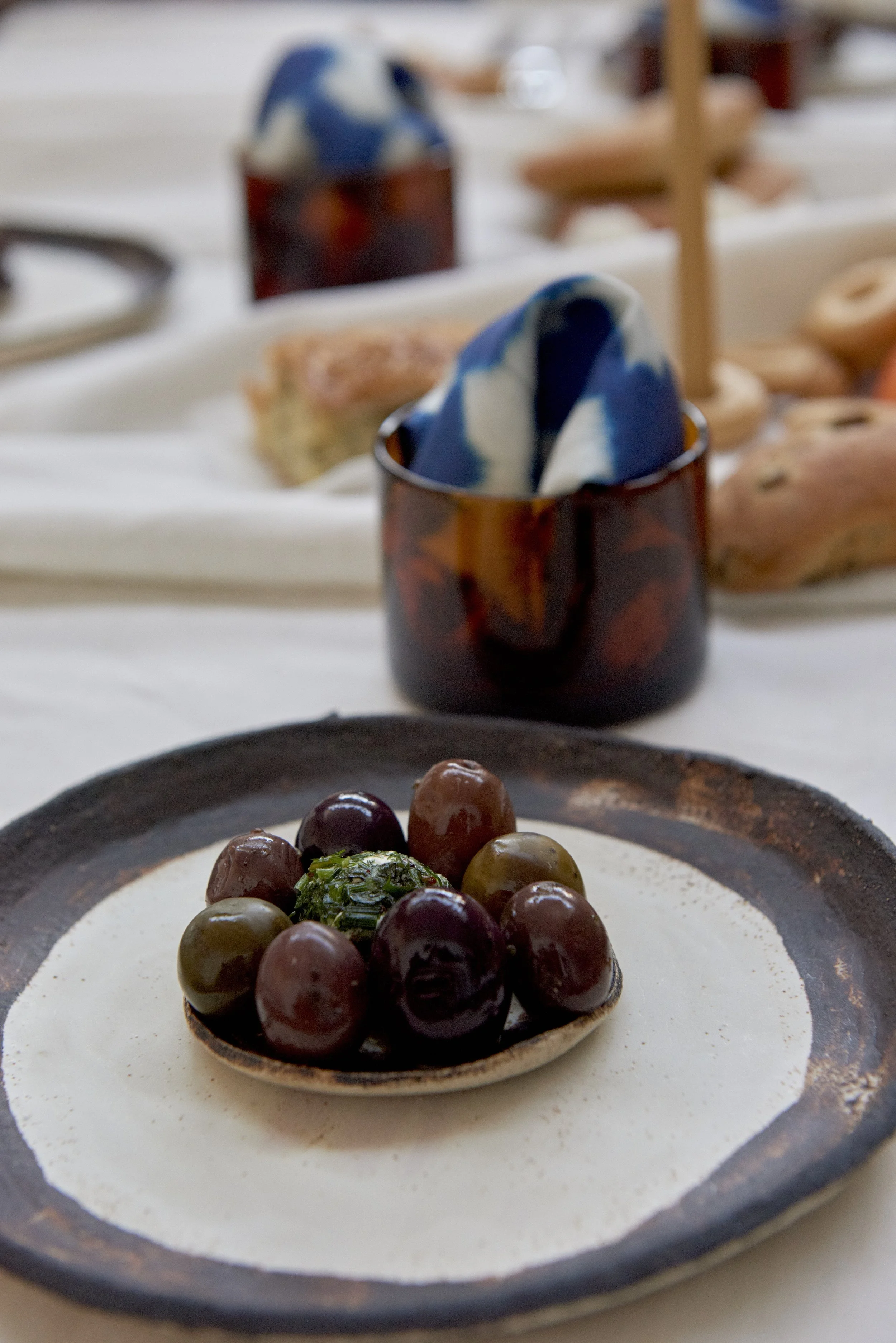 Plated olives on table with amber glass and napkin