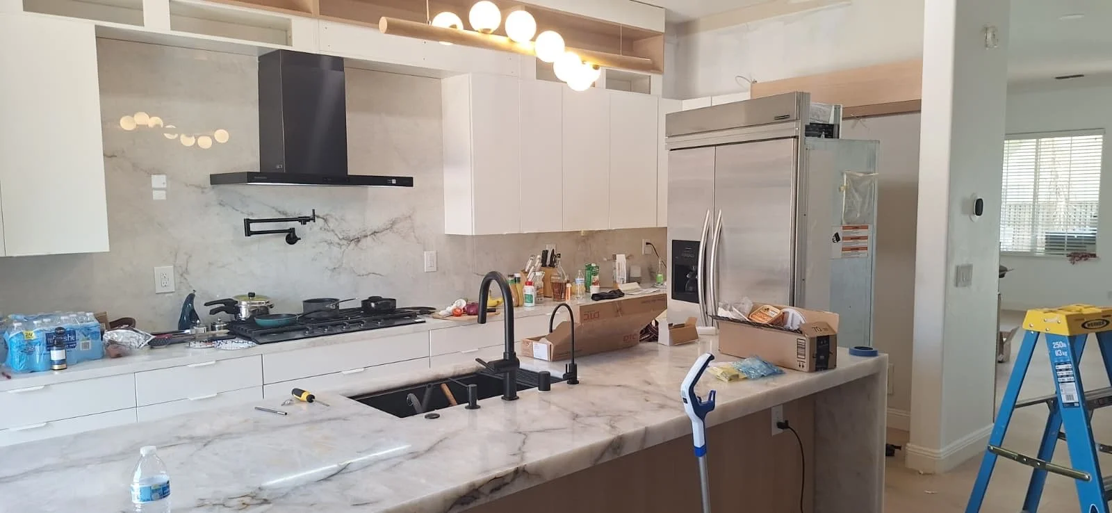 Modern white kitchen remodel with quartz waterfall island, black fixtures, and stainless appliances in the Bay Area