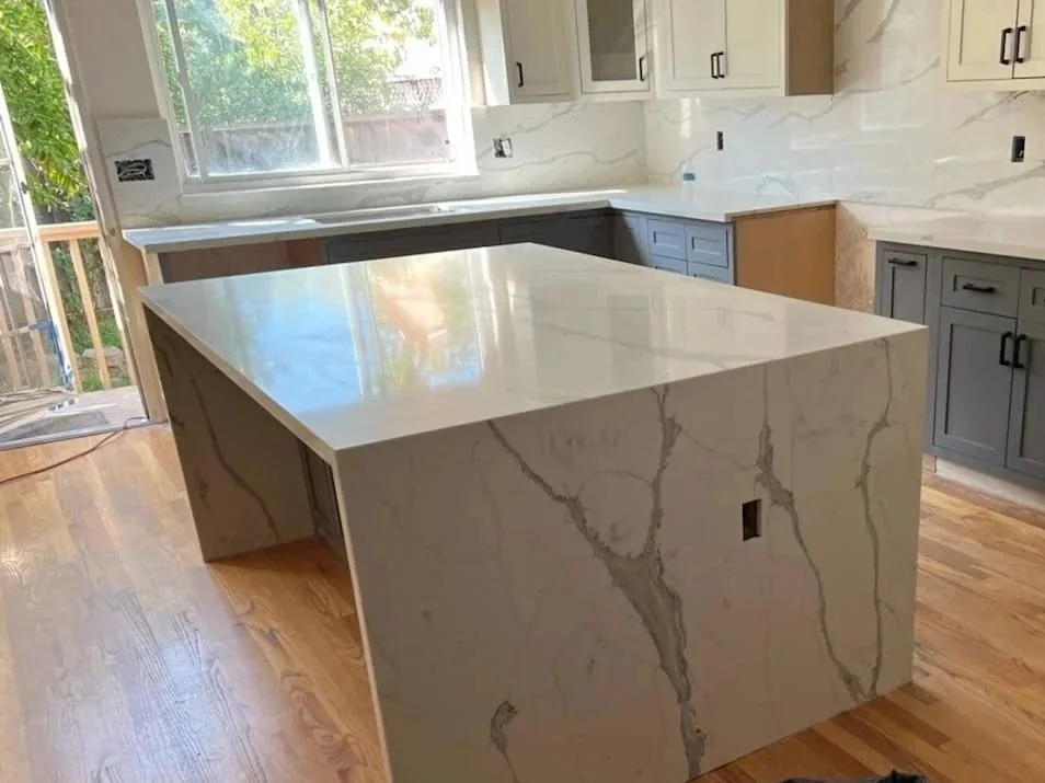 Quartz waterfall island installation with white shaker cabinets and grey base cabinets in Bay Area kitchen remodel