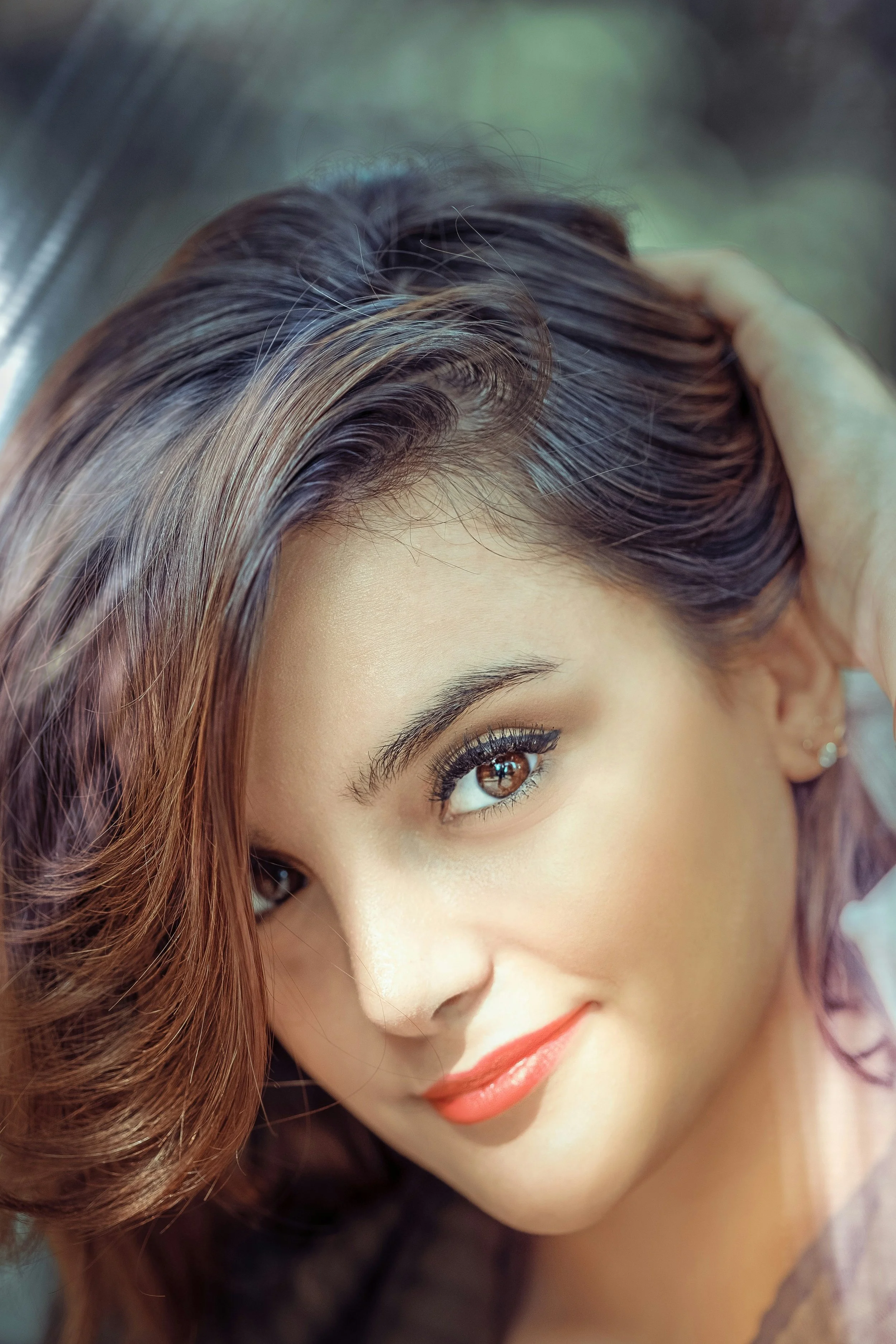 Woman with Gamine face type and a playful smile wearing winged liner and orange lipstick