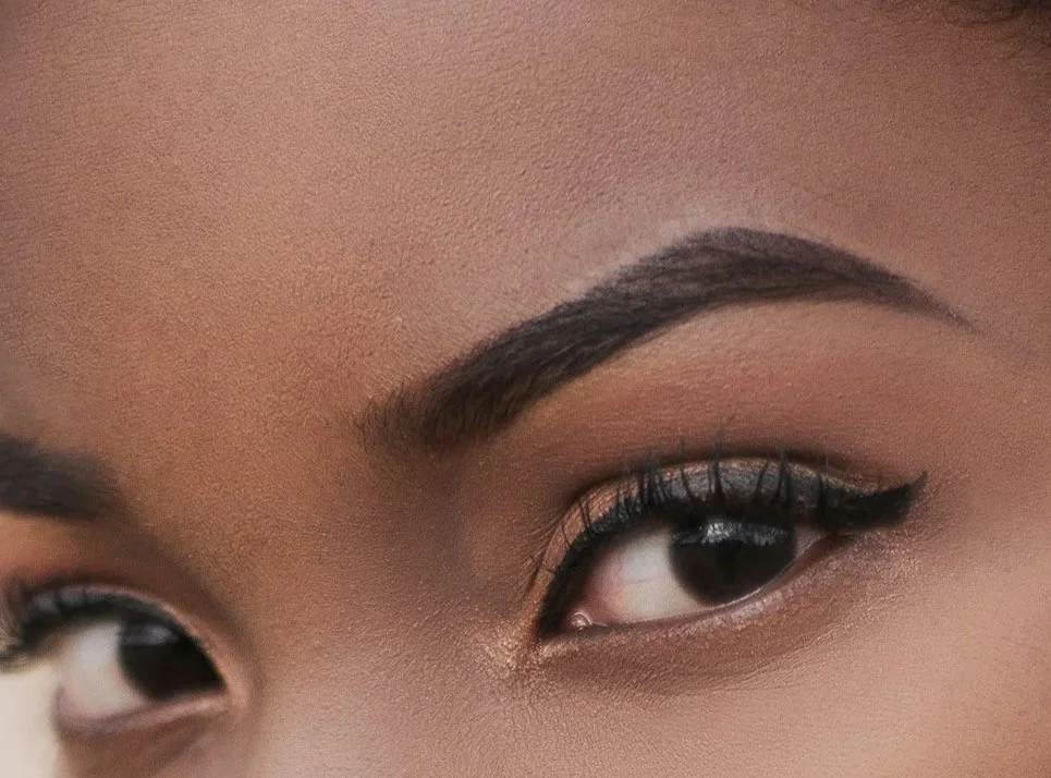 Woman of color wearing thick dark winged eyeliner with an upturned wing