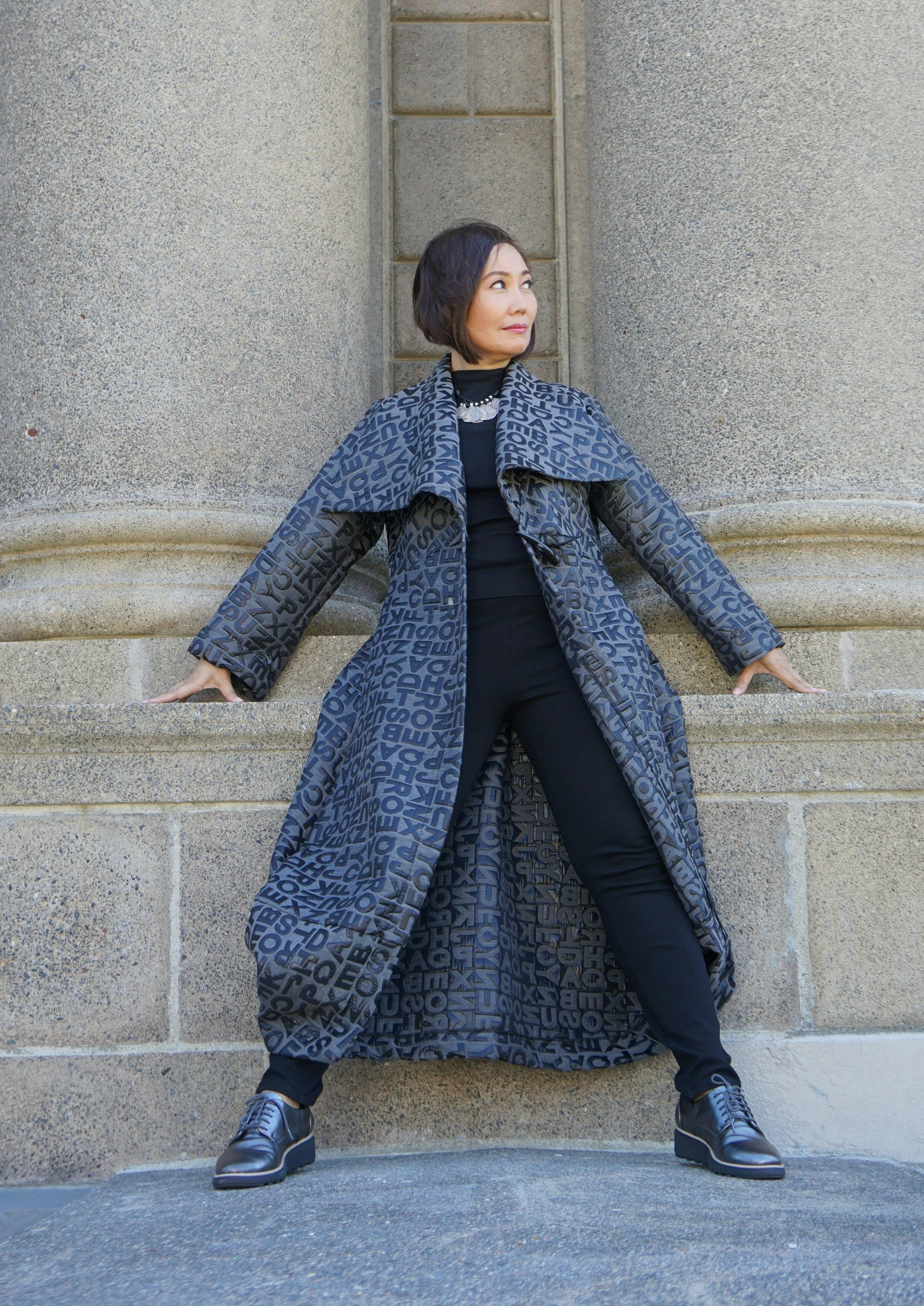 Woman wearing a long blue coat with darkerk blue letter print