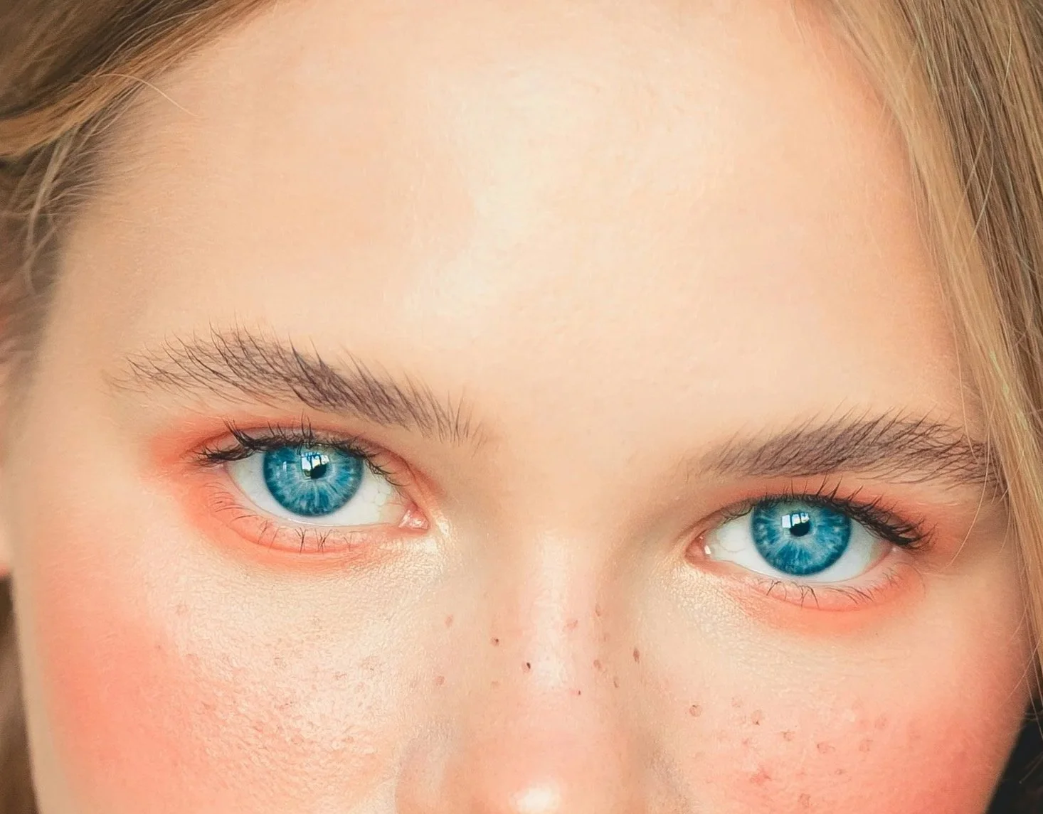 Caucasian model wearing orange eyeshadow all over her eye area