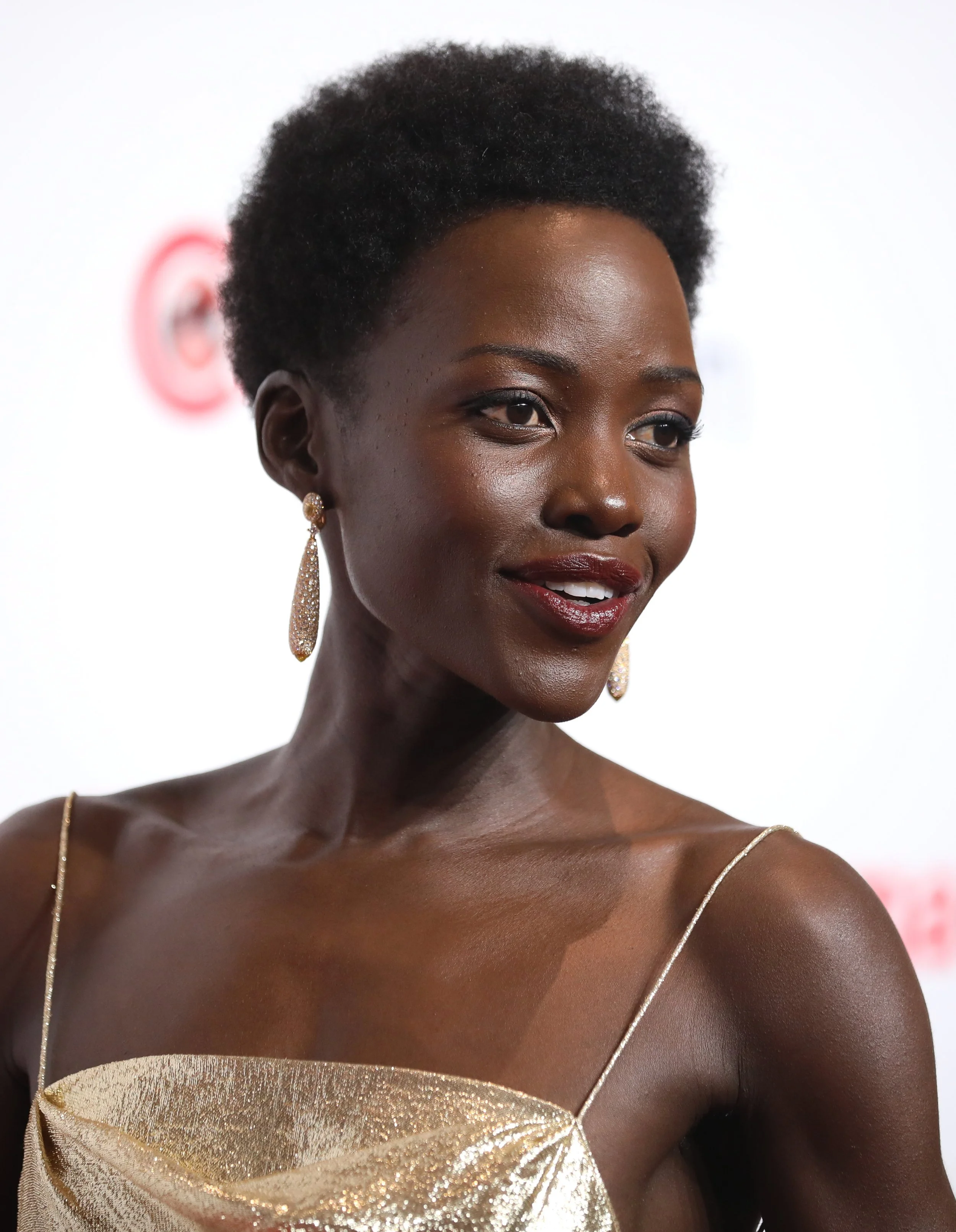 Lupita Nyong'o headshot where she sports light shimmery Ingenue eyeshadow and a deep Dramatic lip, suiting her style id but not her vibrant bright winter (clear winter) color season.