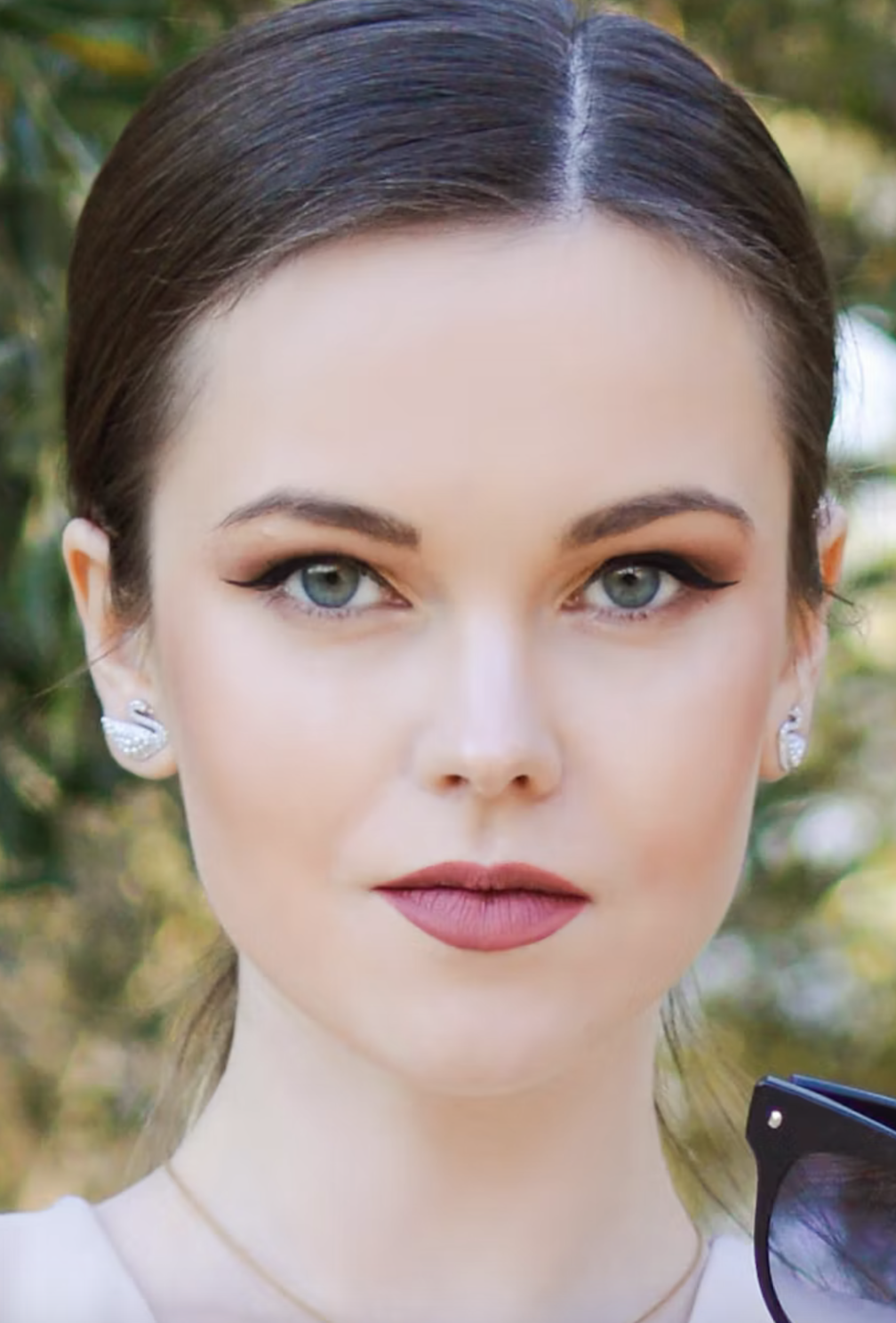 Woman with the Gamine beauty type wearing dark winged liner, orange eyeshadow, and medium pink lipstick