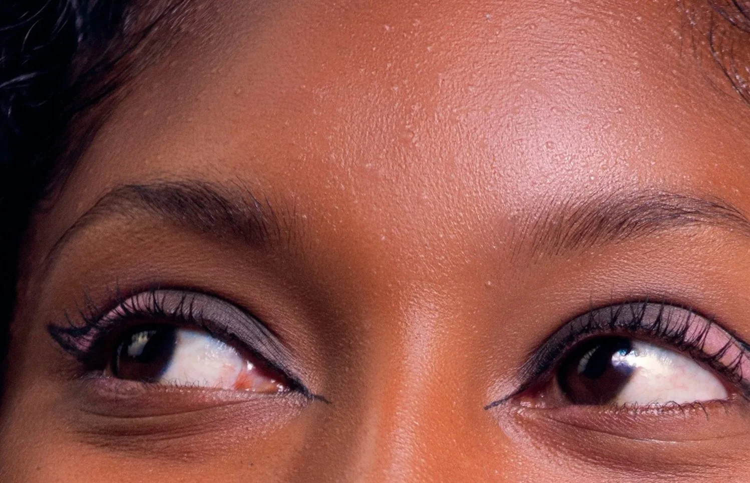 Woman of color wearing negative space eyeliner that highlights her playful, high-spirited beauty
