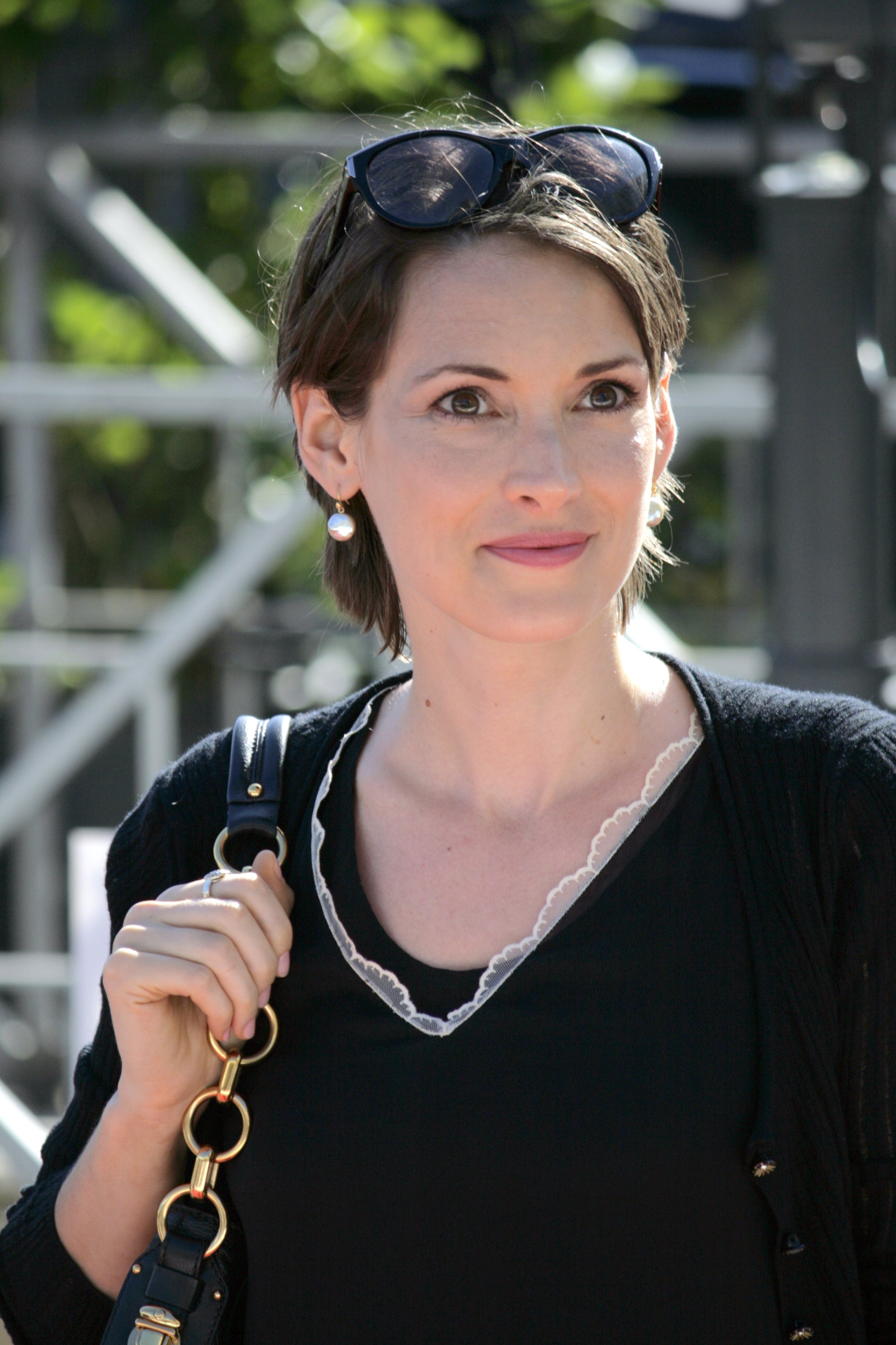 Headshot of Winona Ryder wearing tiny ciruclar Ingenue earrings and scalloped lace and a Dark color palette that suits her Dramatic essence.
