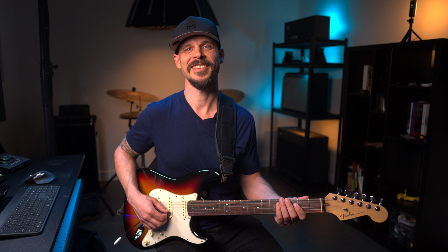 Garrett Ortego smiling while playing guitar in his home studio, welcoming students to online lessons