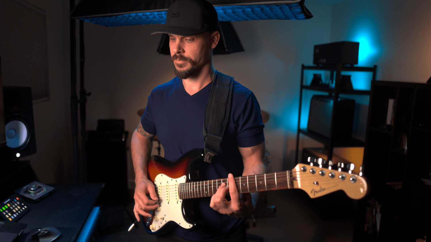 Garrett Ortego standing with his guitar in his private Scottsdale teaching studio, demonstrating a lesson
