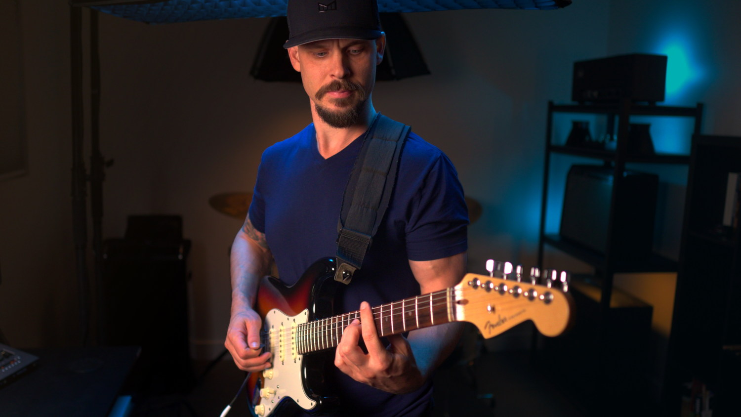 Garrett Ortego standing with his guitar in his Scottsdale teaching studio