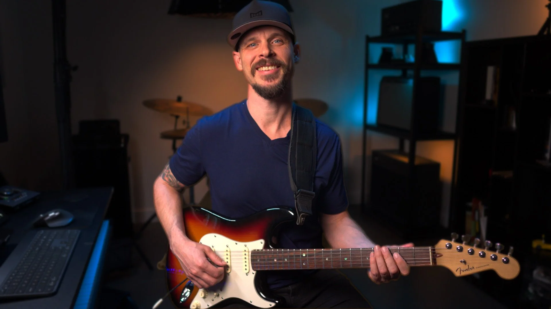 Garrett Ortego smiling while holding a sunburst electric guitar in his studio