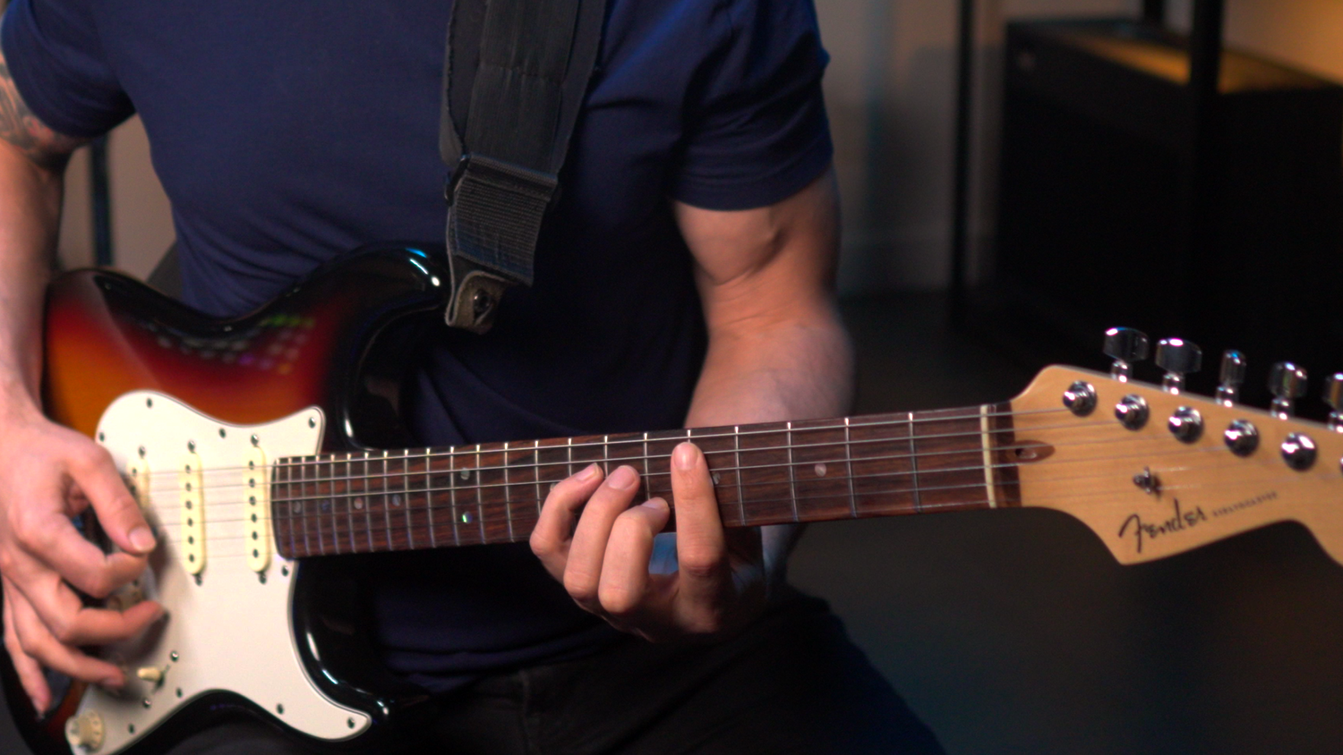 Close-up of hands positioned on a guitar neck and body