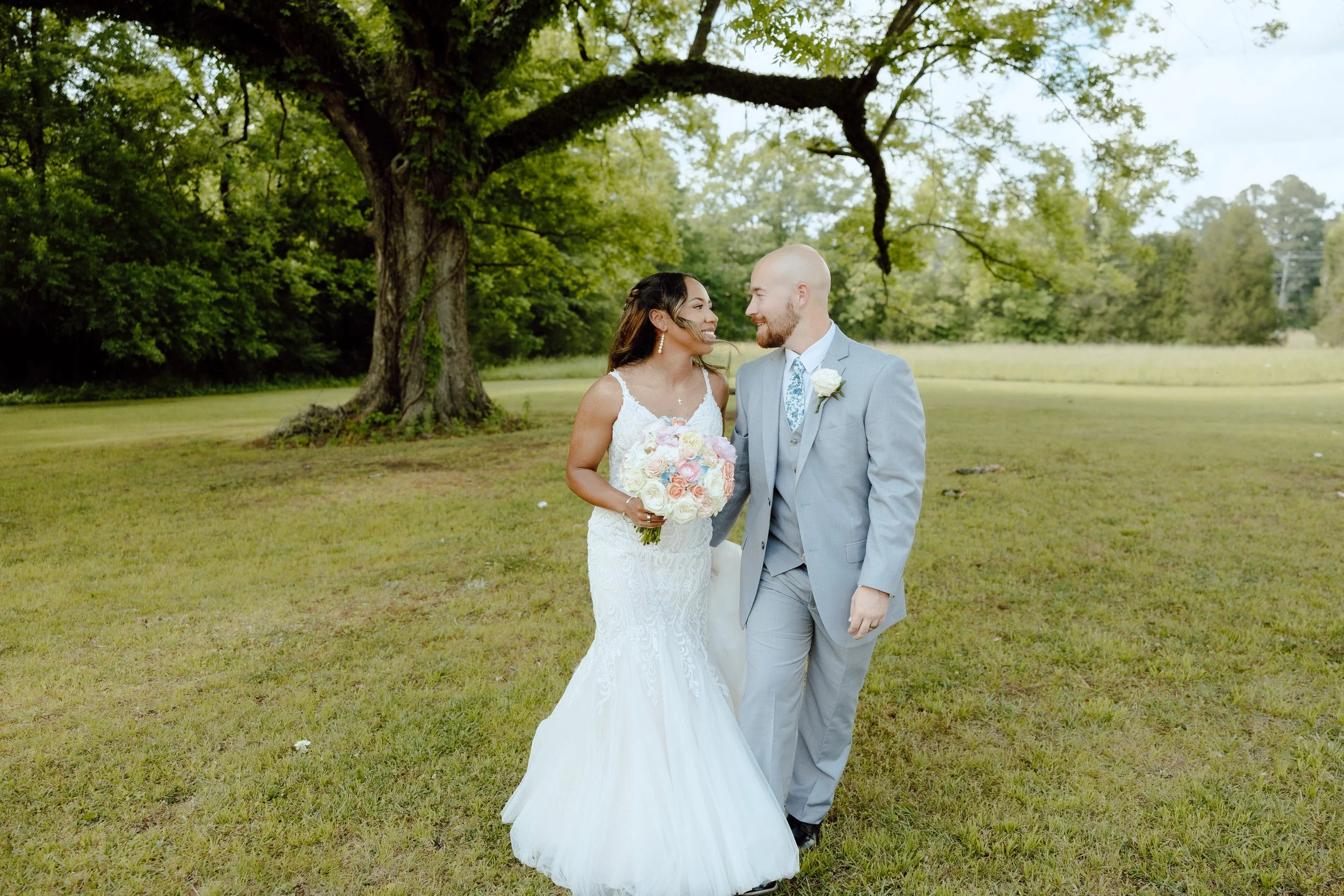 Starkville Mississippi Wedding, Bride and Groom walking with bouqet in green landscape